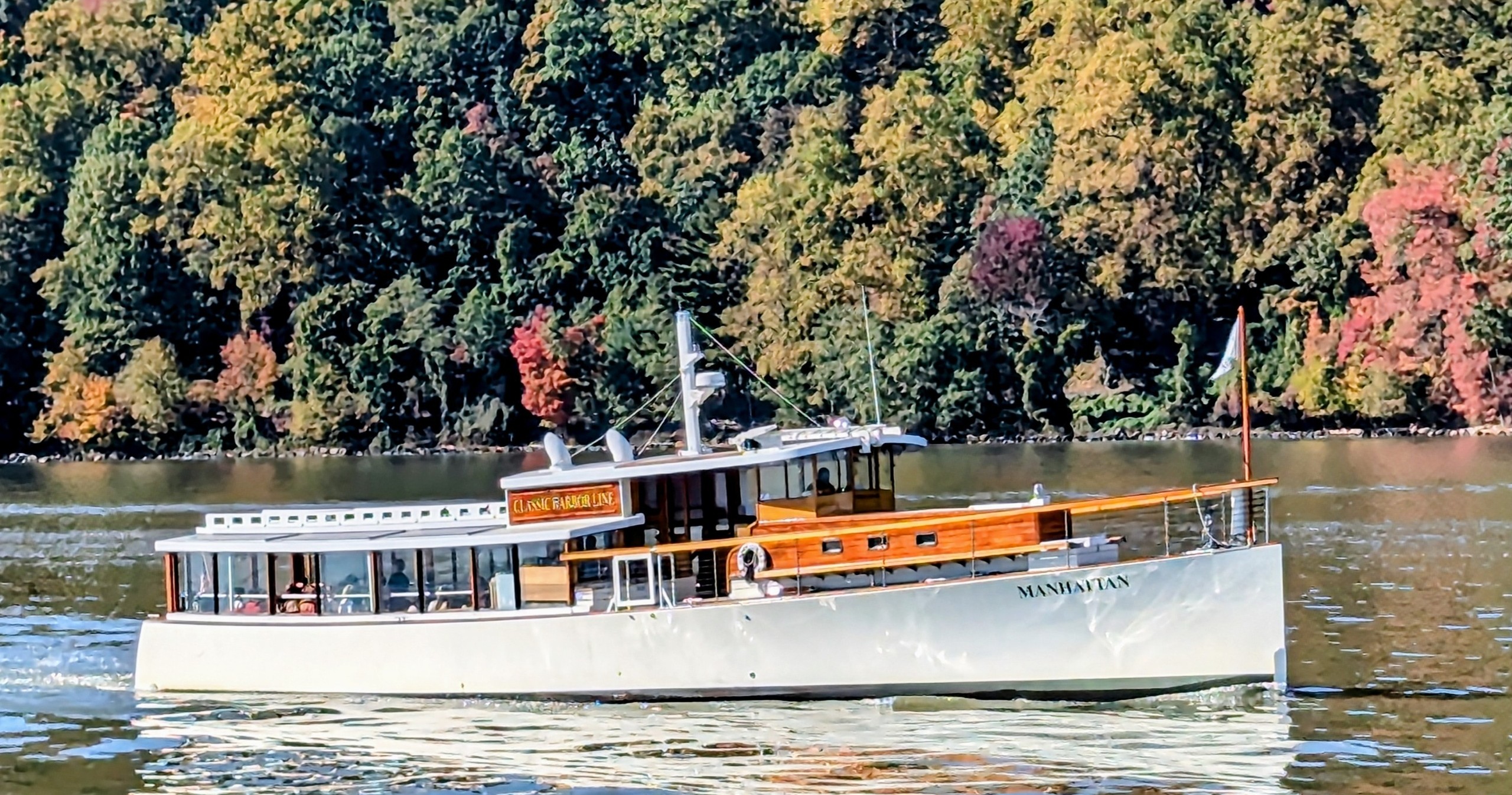 Vintage boat on a river with autumn trees in the background.
