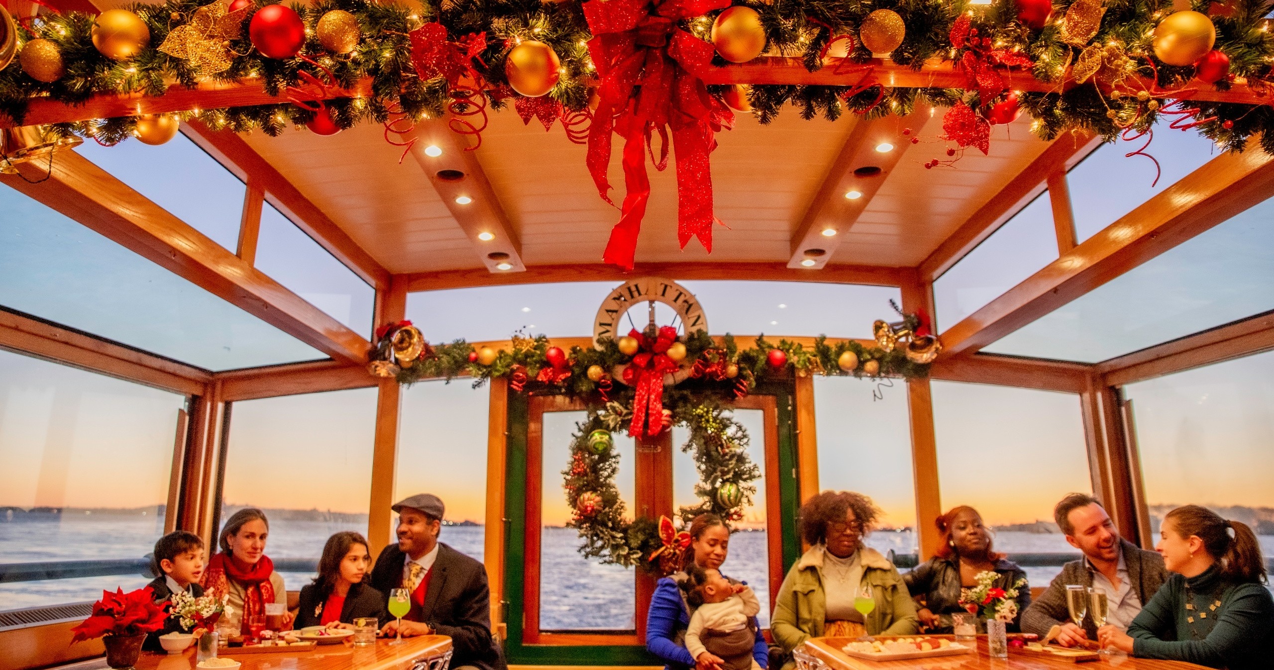 People dining on a festively decorated boat with wreaths and garlands.