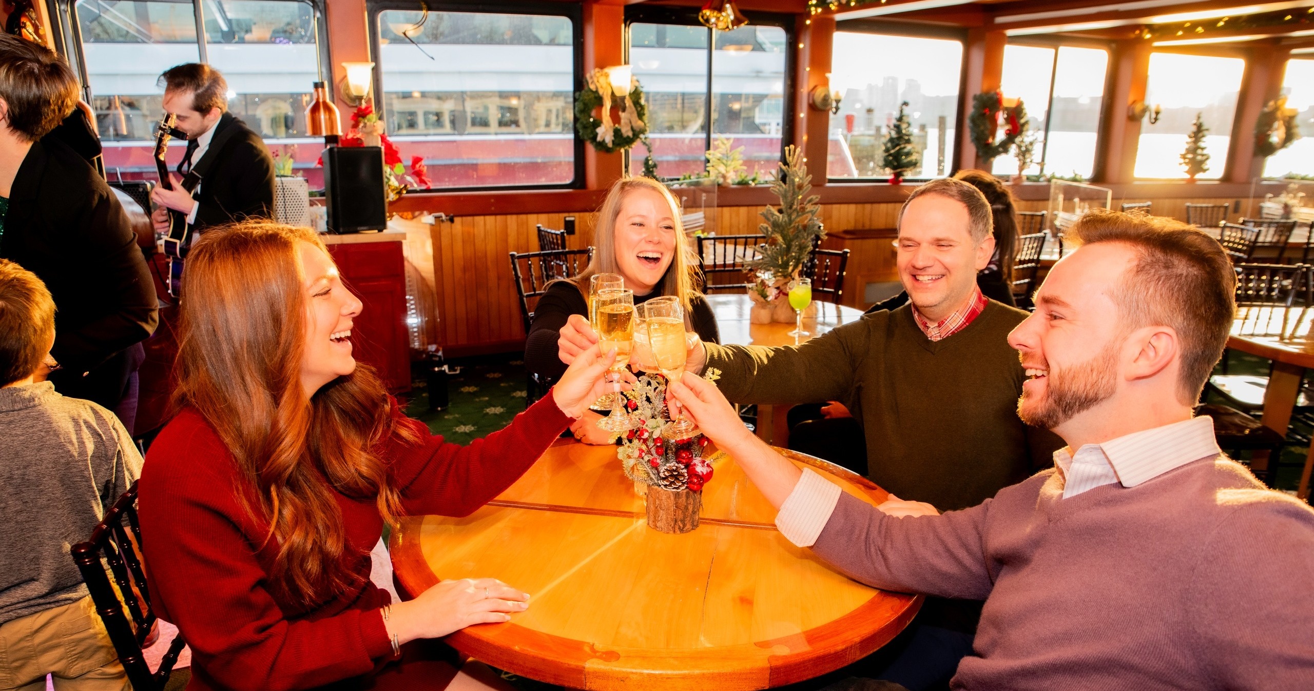Four people toasting glasses around a festive round table.