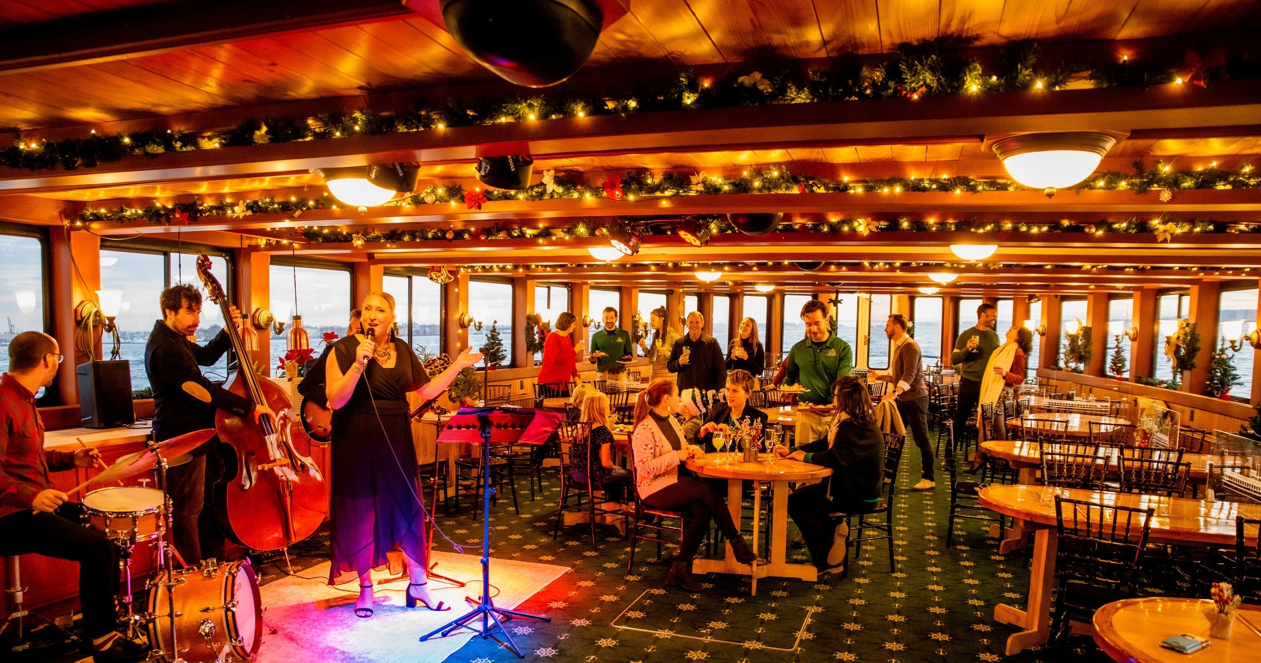 Band performing in festive, decorated restaurant with audience seated at tables.
