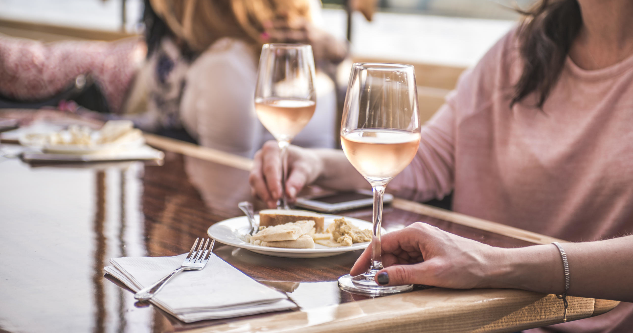 Two people at a table with wine and plates of food.