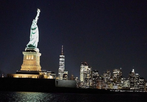 Statue of Liberty at night with city skyline in the background.