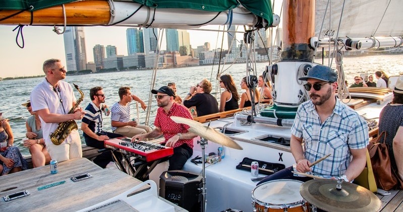 Band playing music on a boat with city skyline in the background.