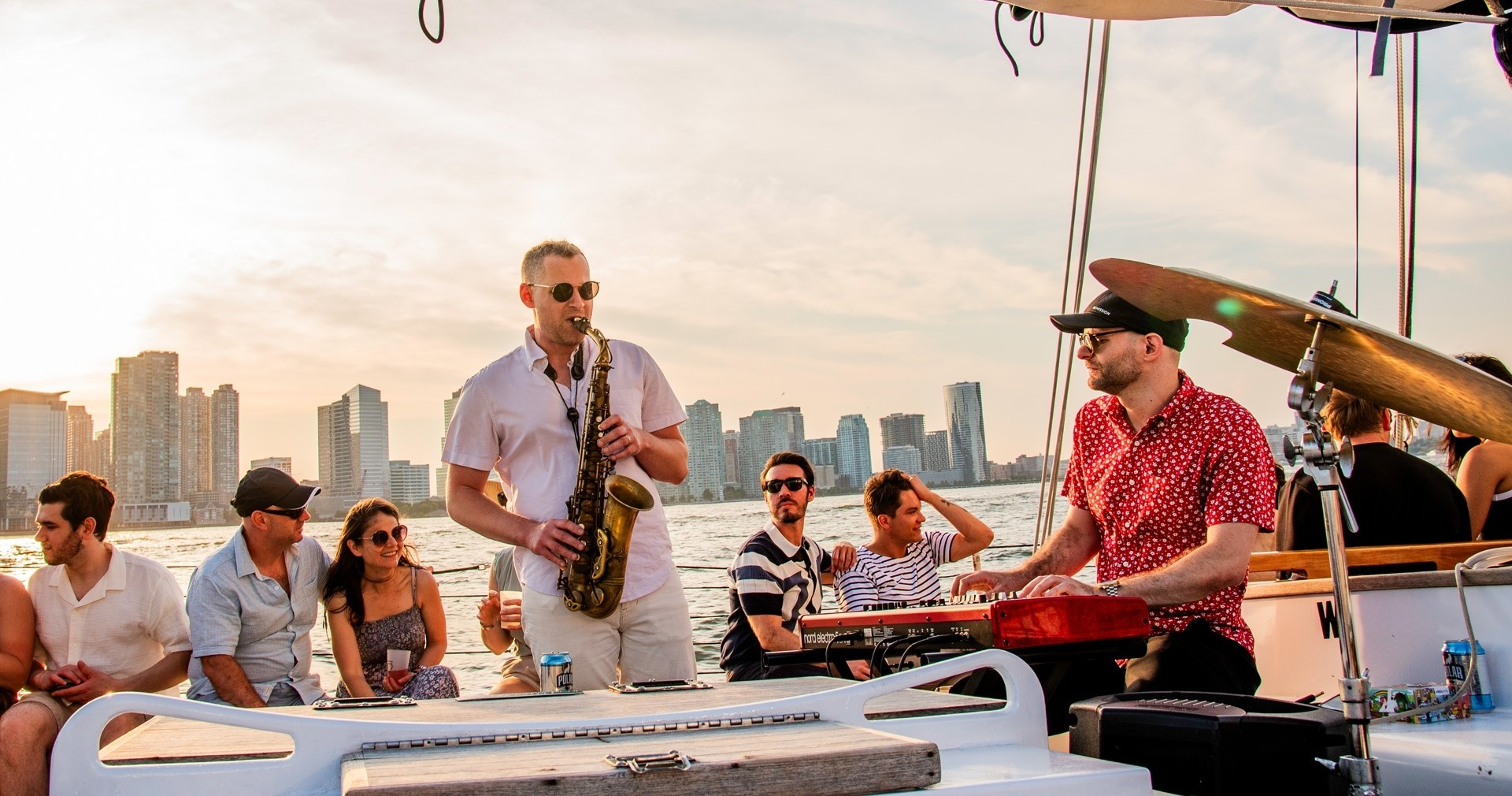 People enjoying live music on a boat with city skyline in background.