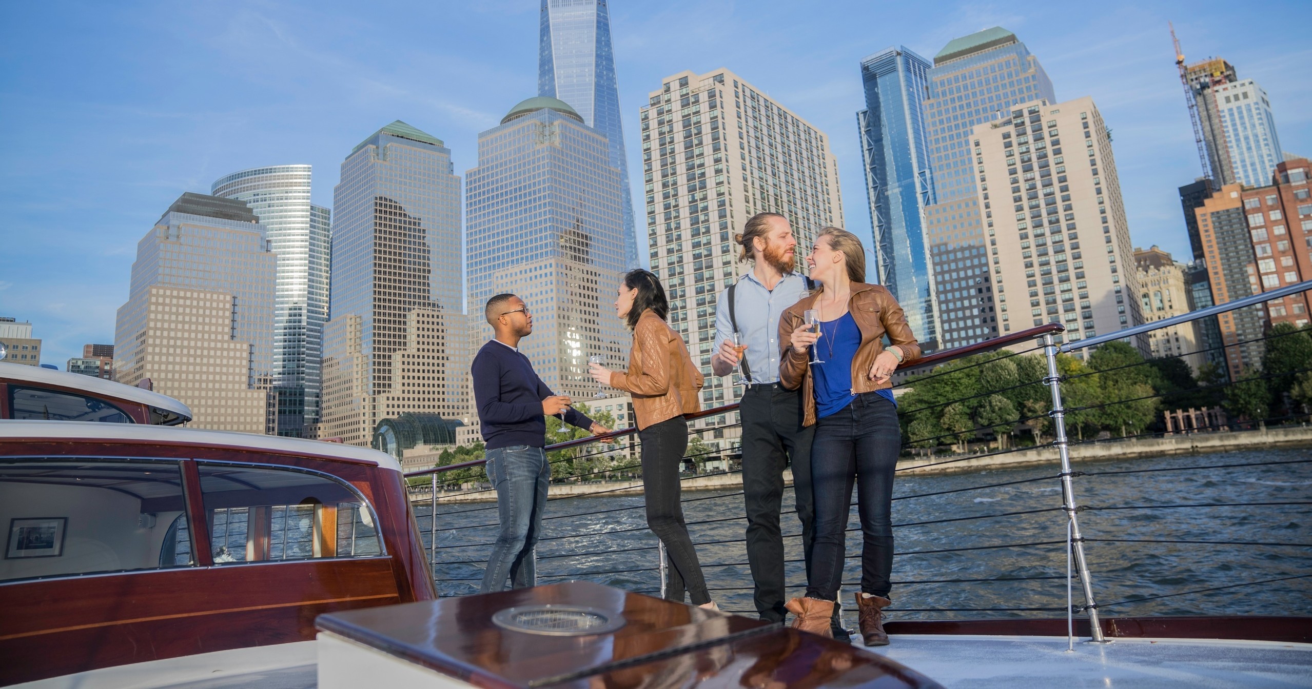 Four people on a boat with a city skyline in the background.