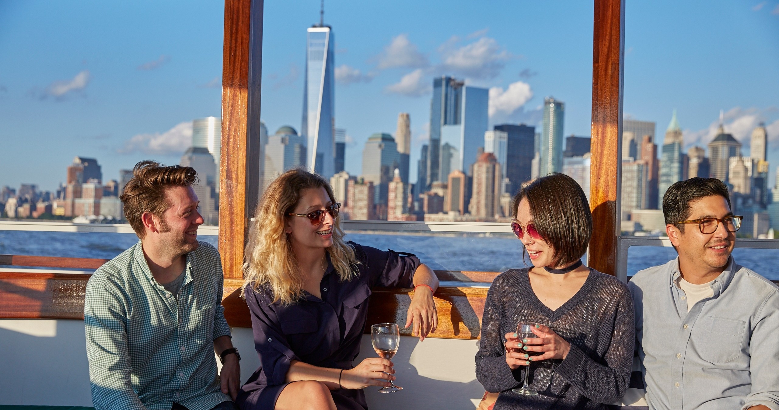 Four people on a boat with New York City skyline in the background.