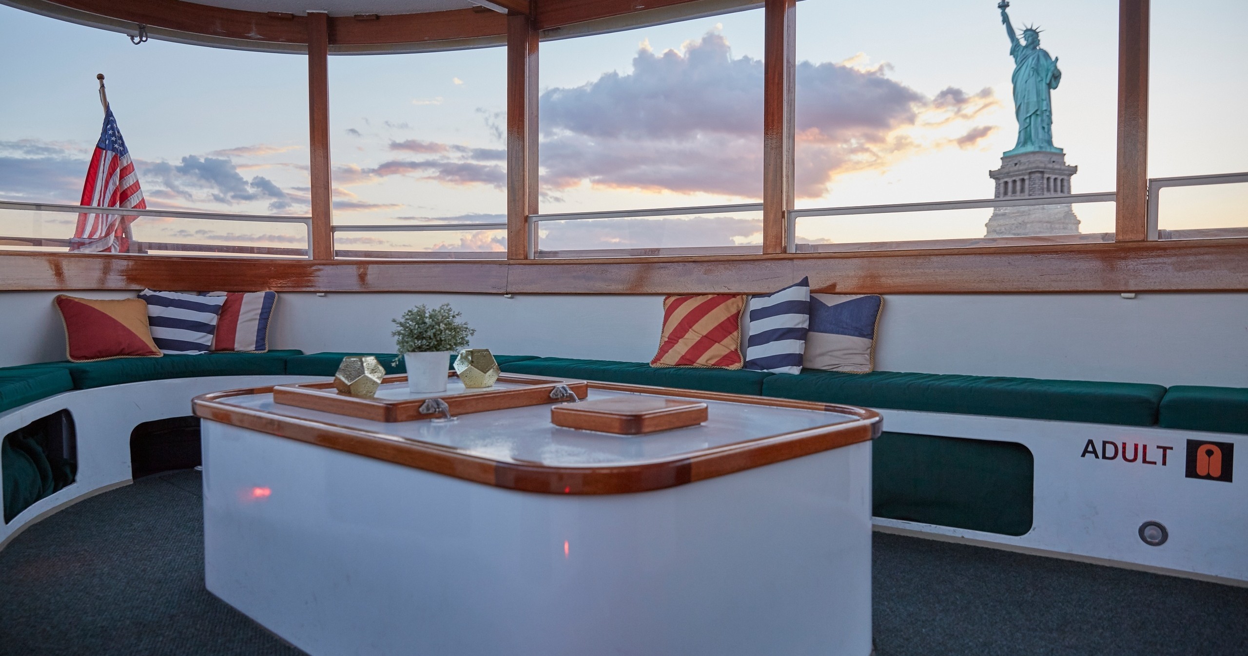 Boat cabin with Statue of Liberty view, flags, and cushions.