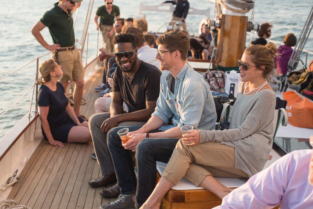 People laughing and relaxing on a sailboat deck on a sunny day.