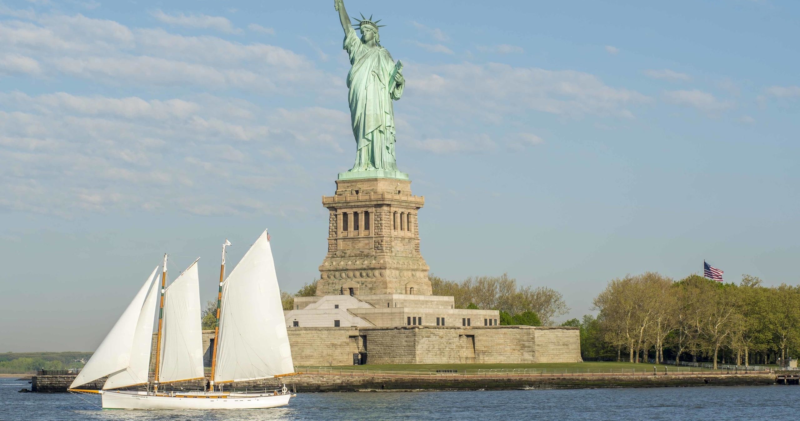 Sailboat on water near the Statue of Liberty against a clear sky.
