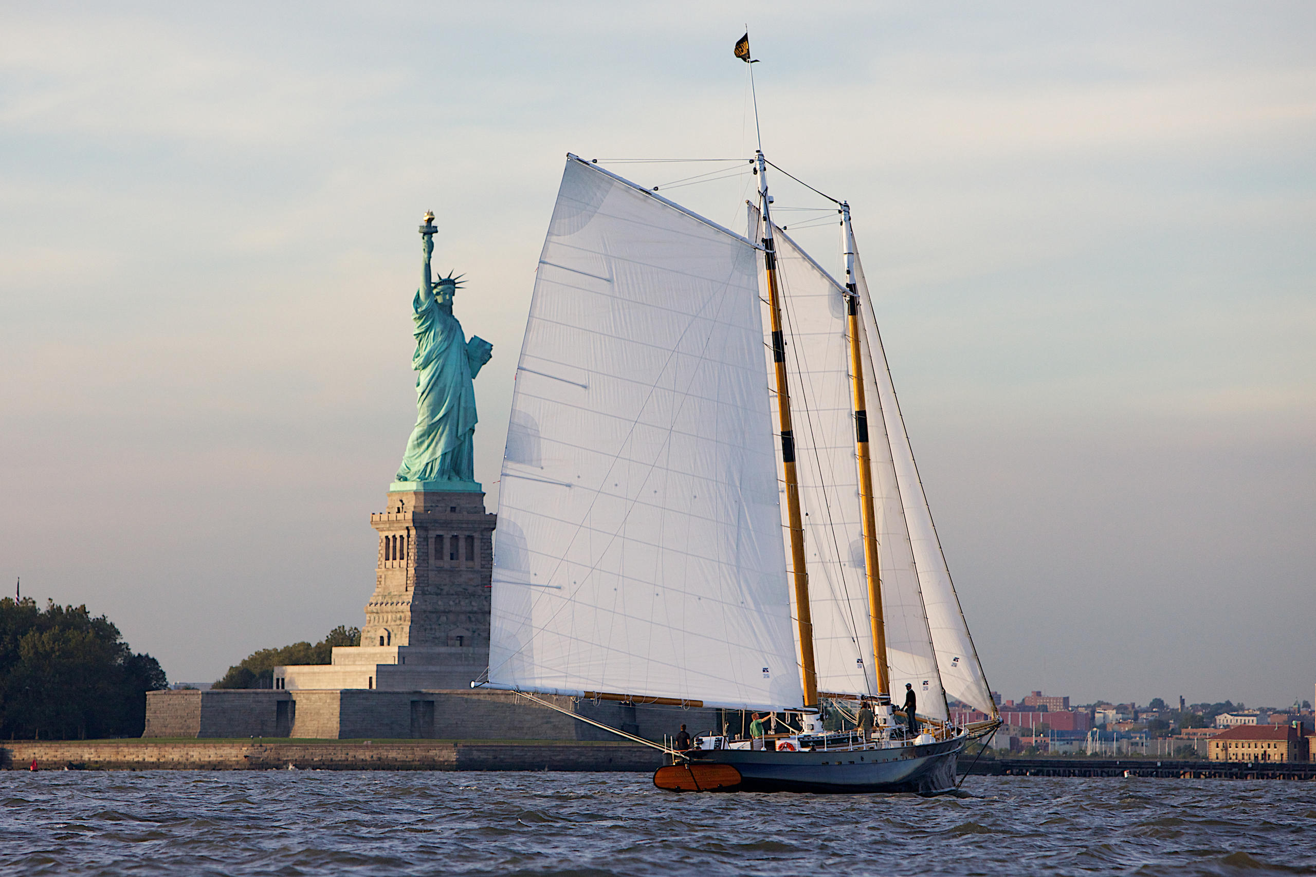 Sailboat near the Statue of Liberty on a cloudy day.