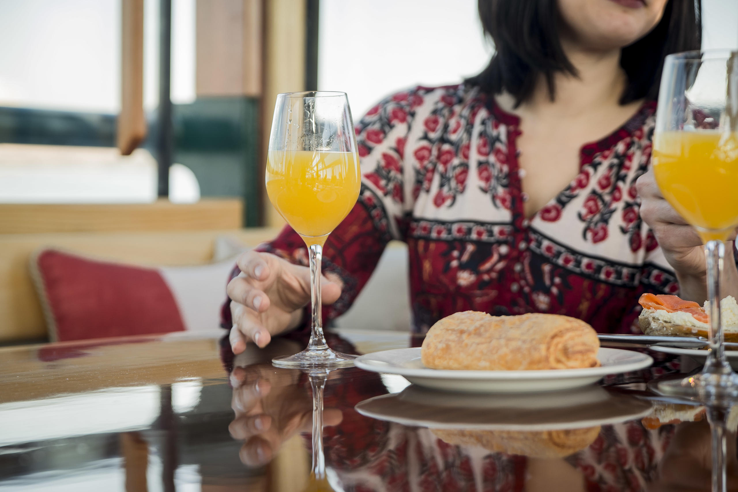 Person with orange drink and pastry on a table.