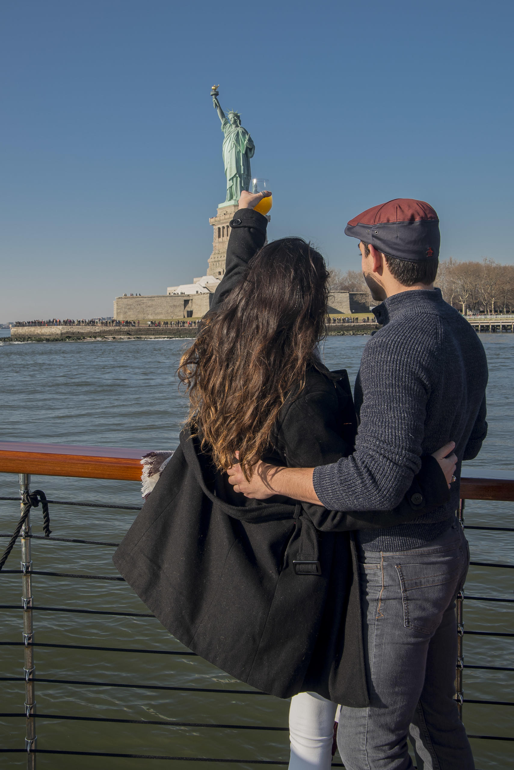 Couple on a boat admiring the Statue of Liberty on a clear day.