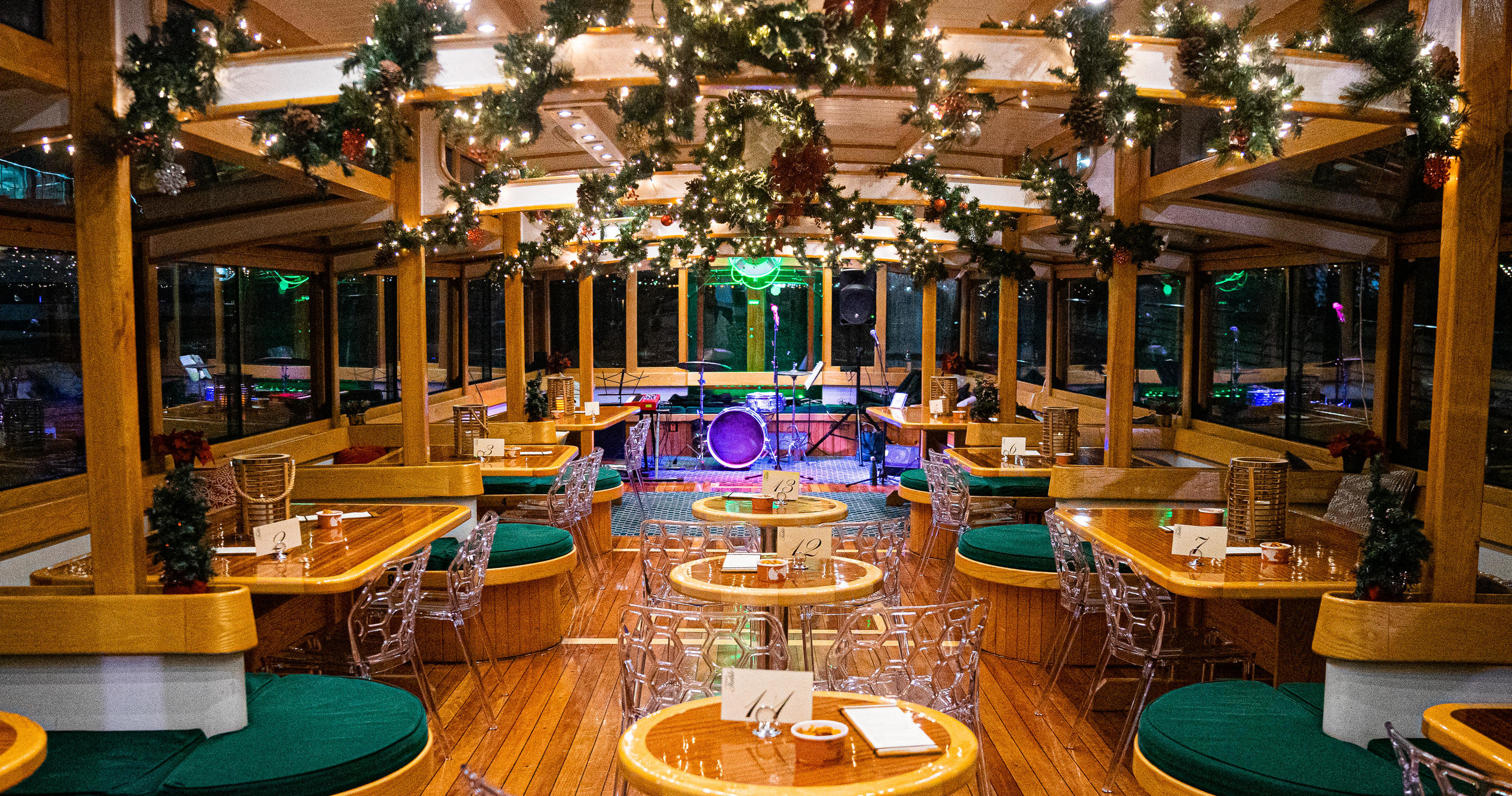 Festive restaurant interior with holiday decorations and circular tables with green chairs.