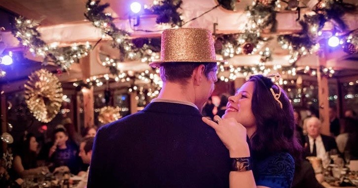 Couple dancing at festive event with lights and decorations.