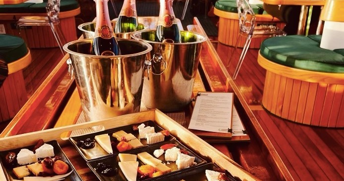 Cheese and fruit platters with champagne in ice buckets on a wooden table.