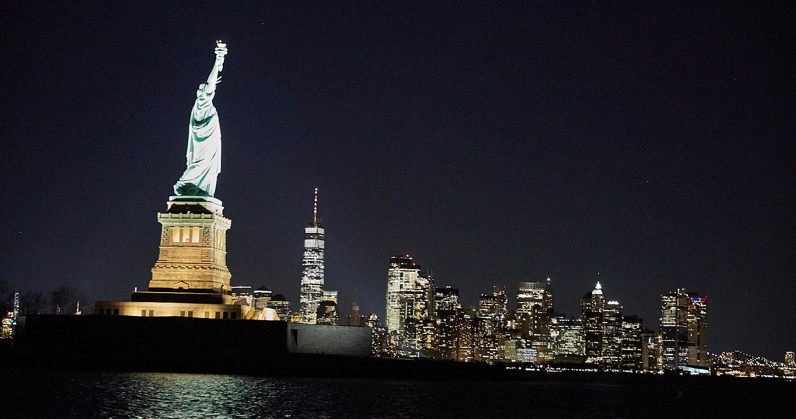 Statue of Liberty and New York City skyline at night.