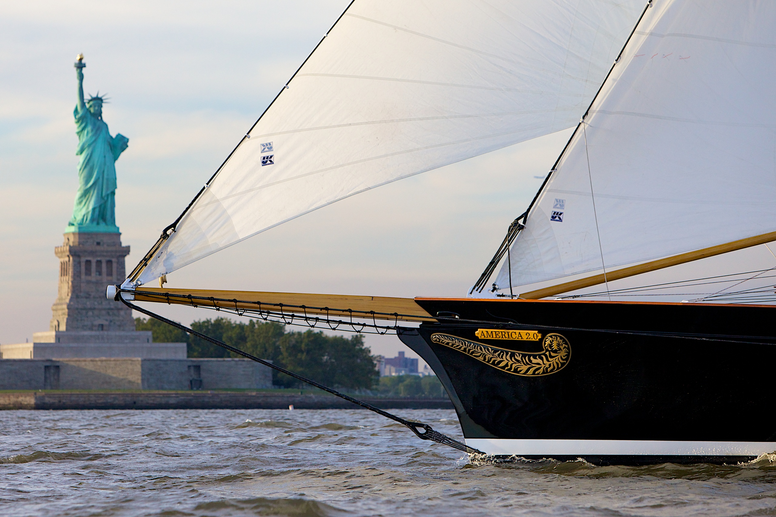 Sailboat on water near the Statue of Liberty on a clear day.