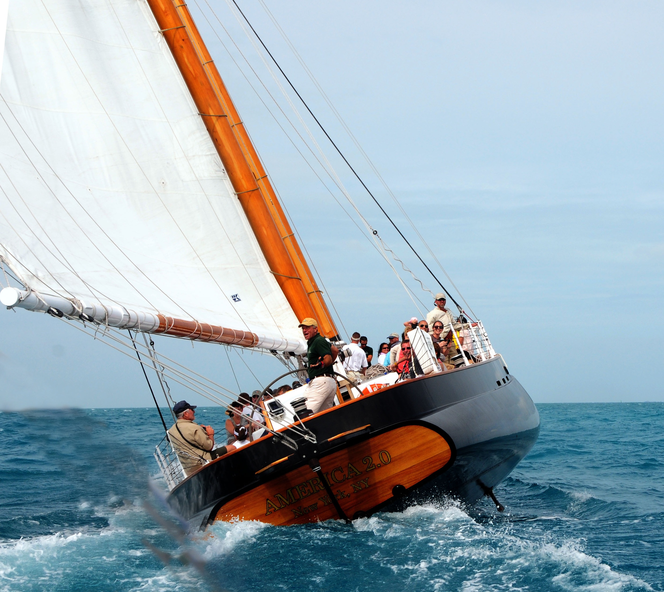 Sailing yacht with crew, tilted on the ocean with full white sails.