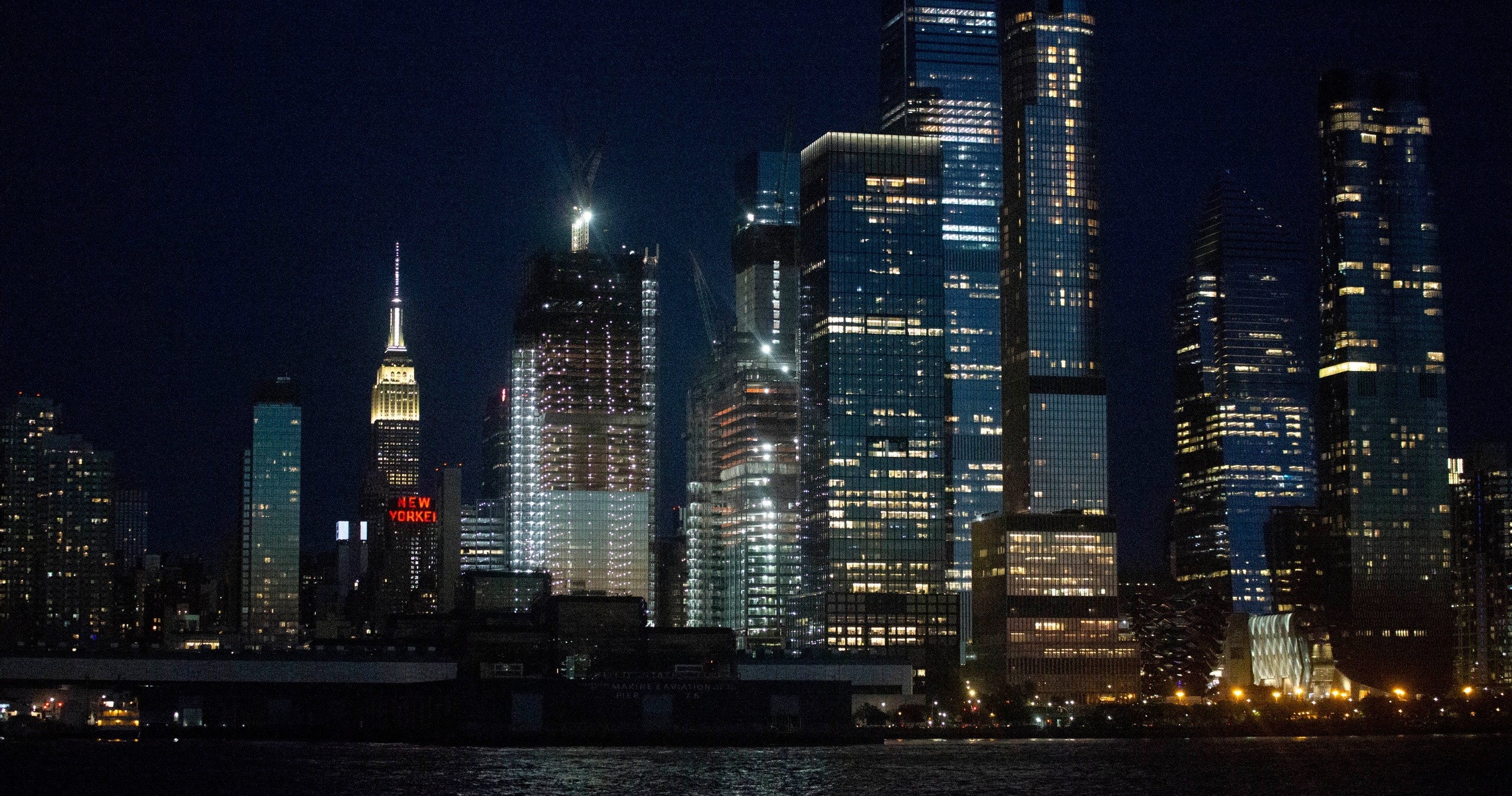 Night view of illuminated city skyscrapers along a river.