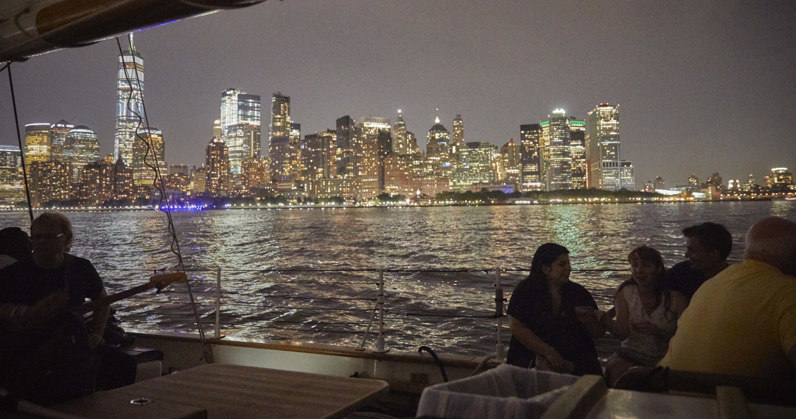 People on a boat at night with a city skyline in the background.