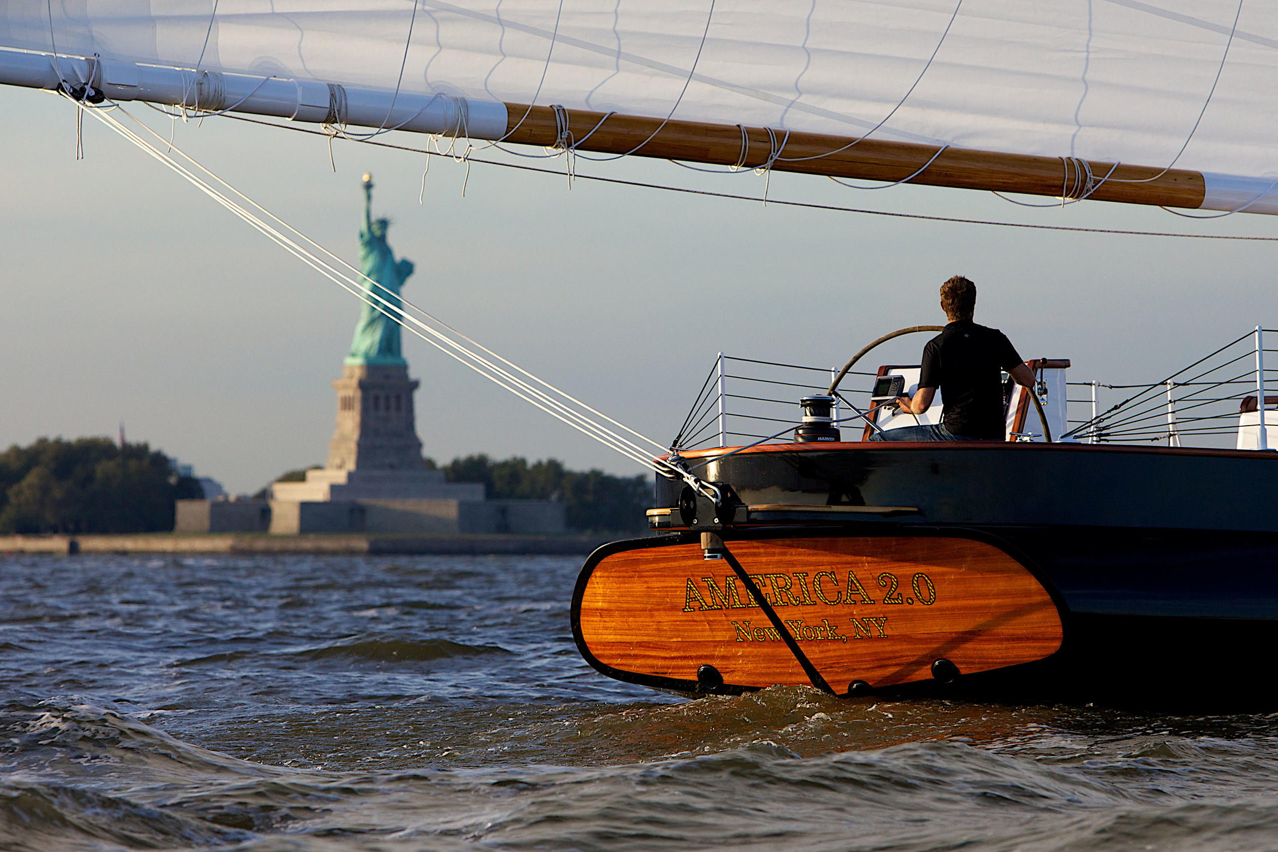 Sailboat on water with Statue of Liberty in the background.