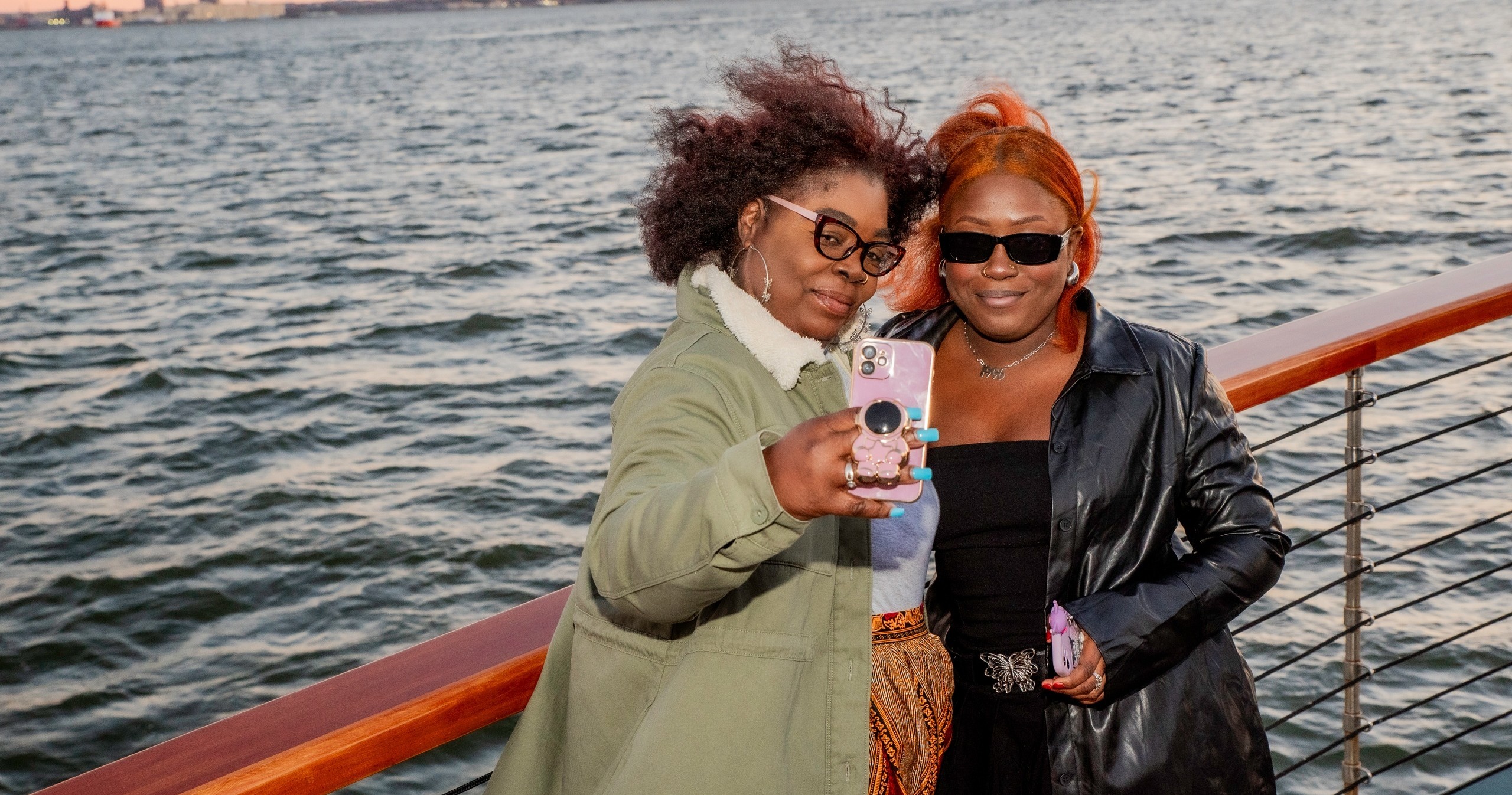 Two people on a boat taking a selfie with water in the background.