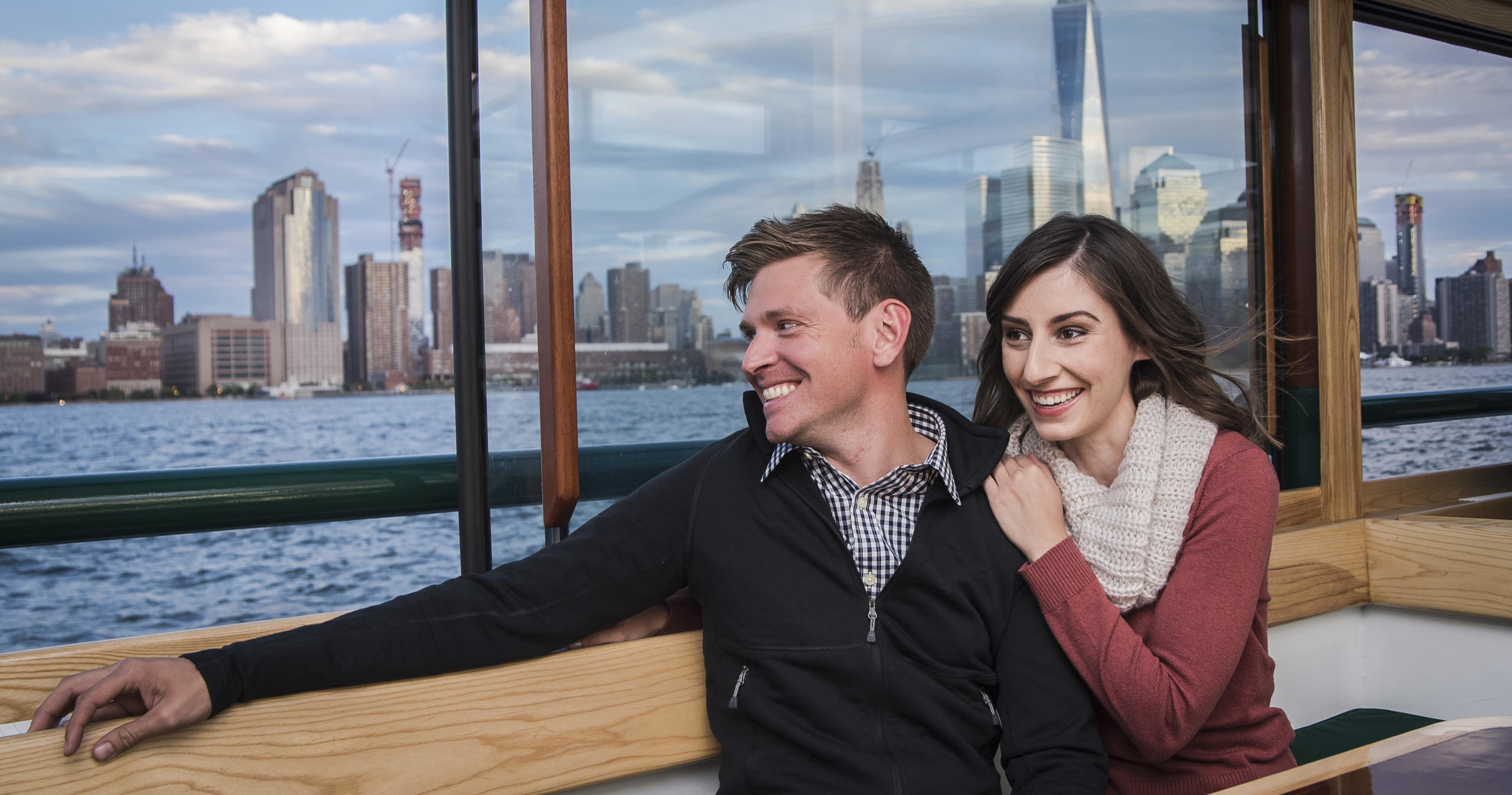 Couple sitting on a boat with a city skyline in the background.
