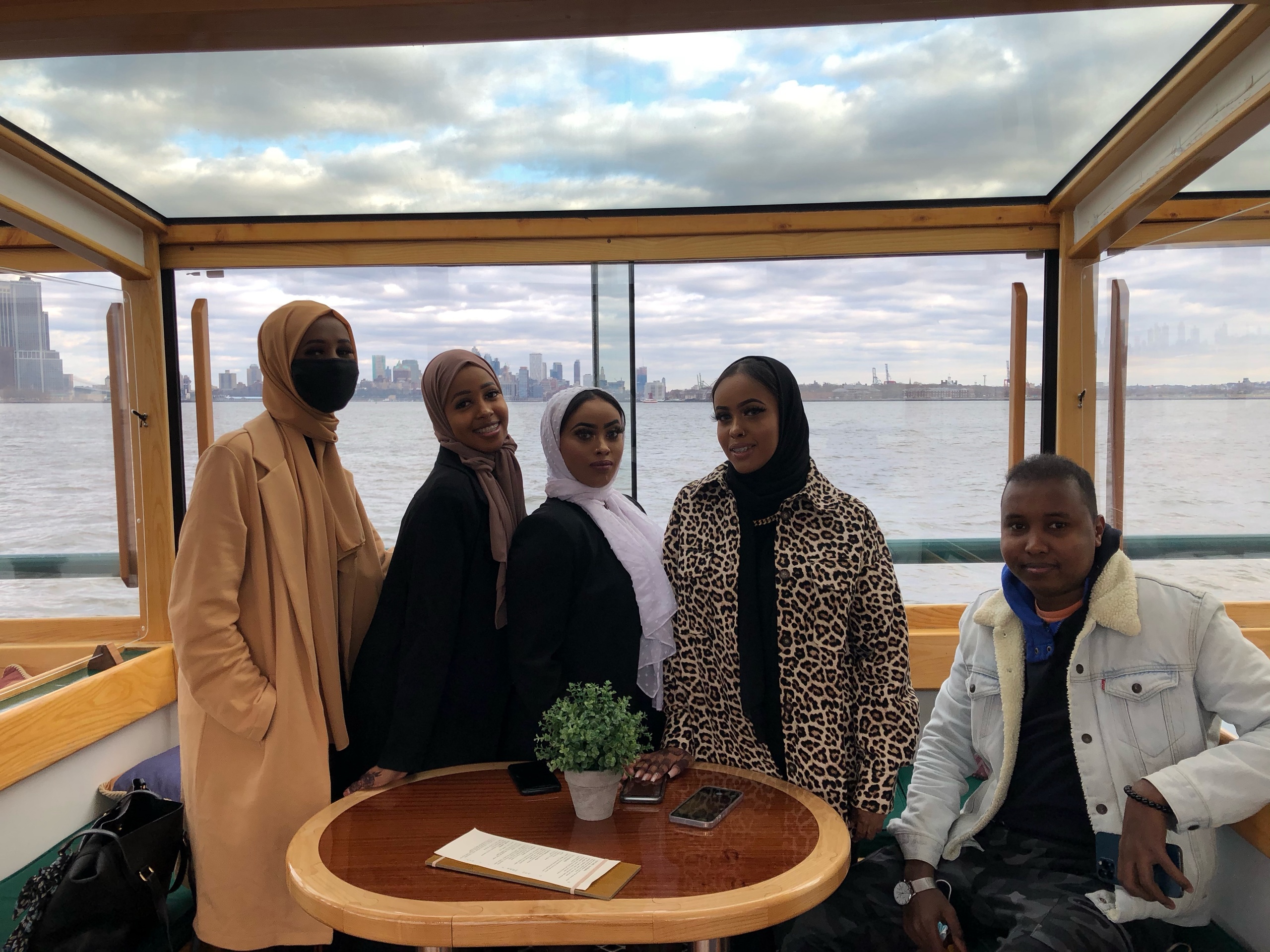 Group of people in winter clothing on a boat with city skyline view.