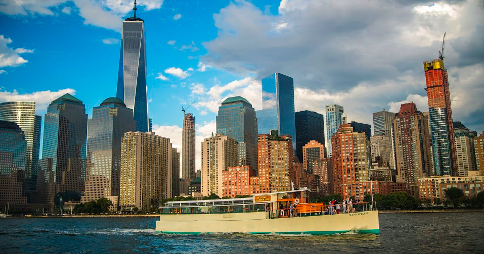 Boat on water with a city skyline and a tall skyscraper in the background.