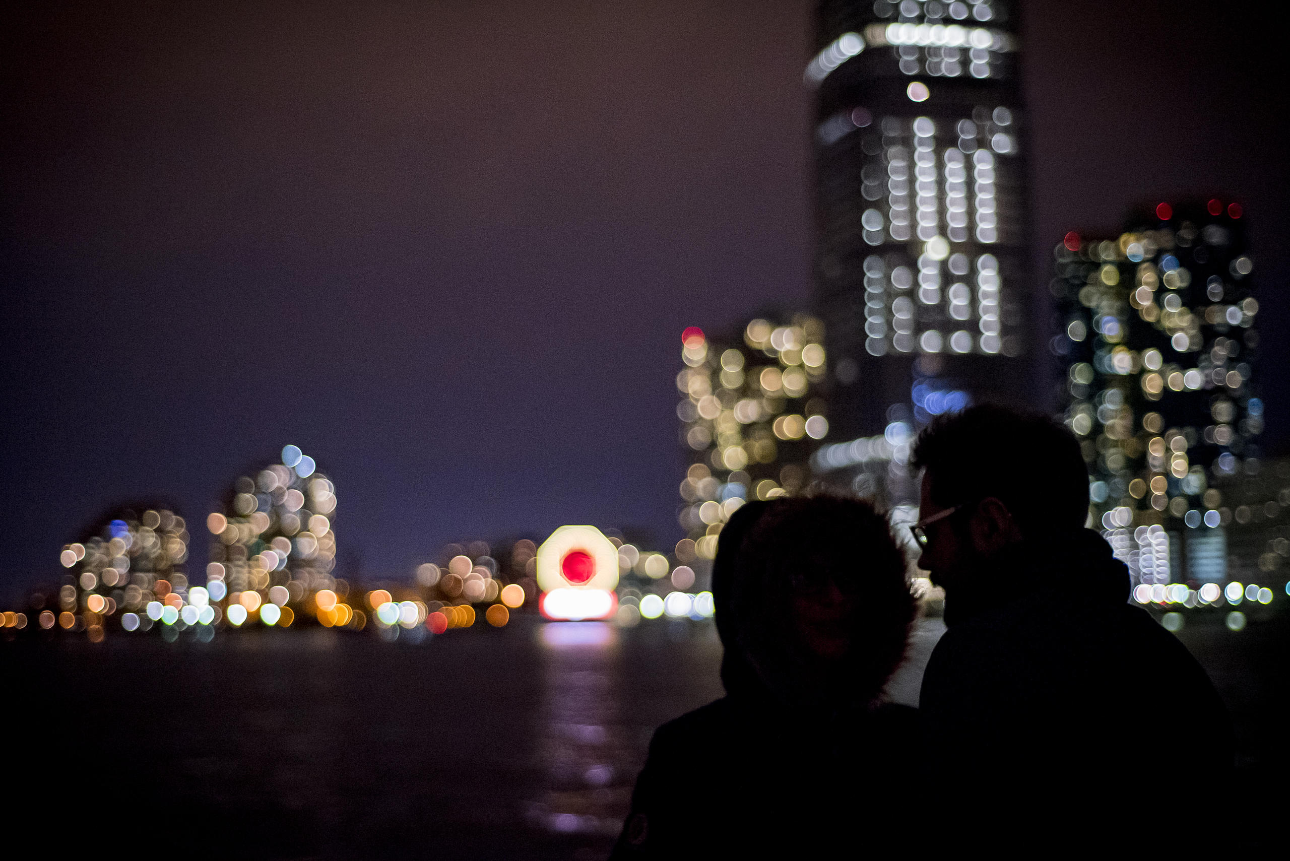 Silhouetted couple against blurred city lights at night.