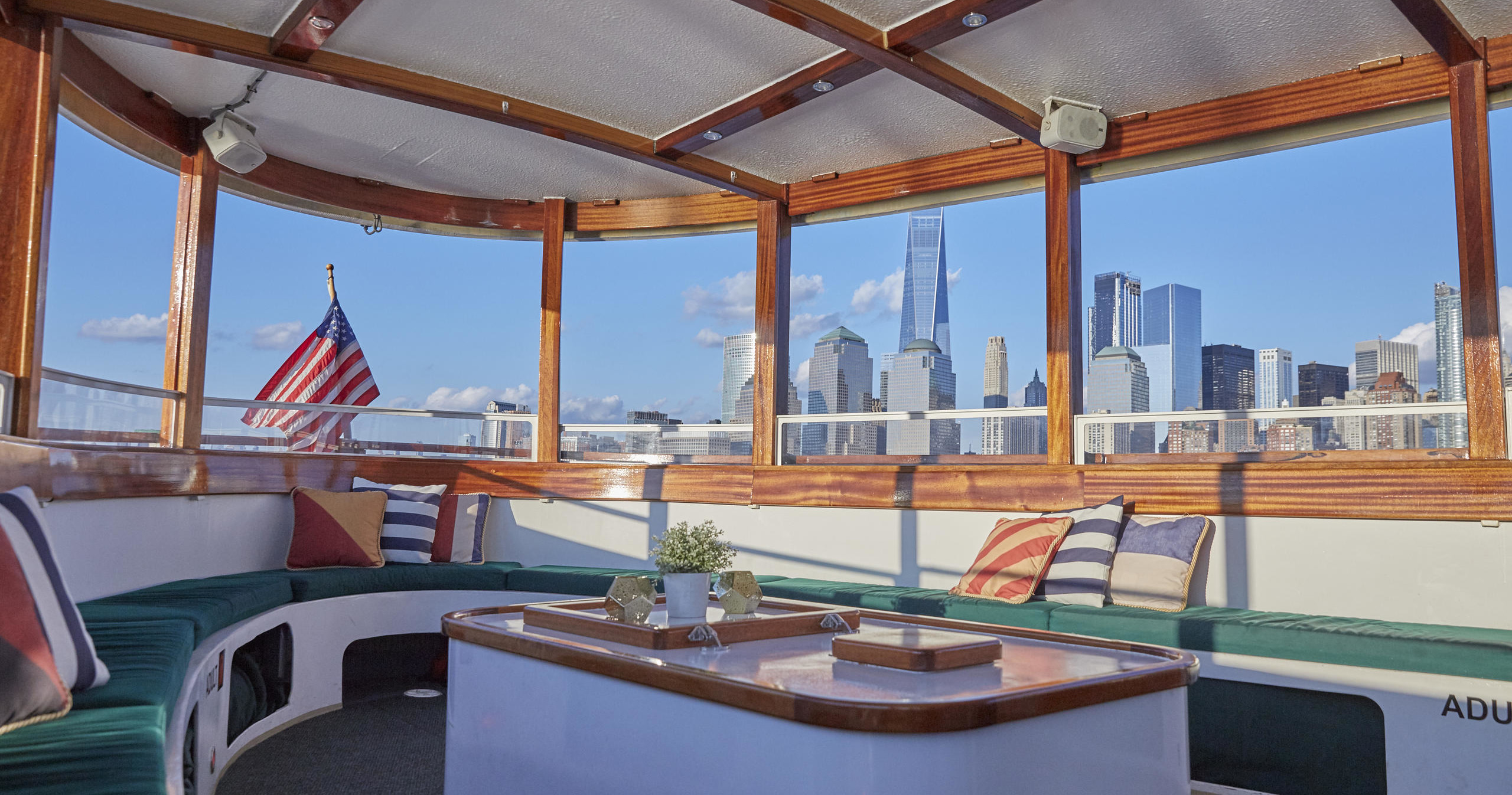 Cozy boat interior with city skyline view, flag flying outside.