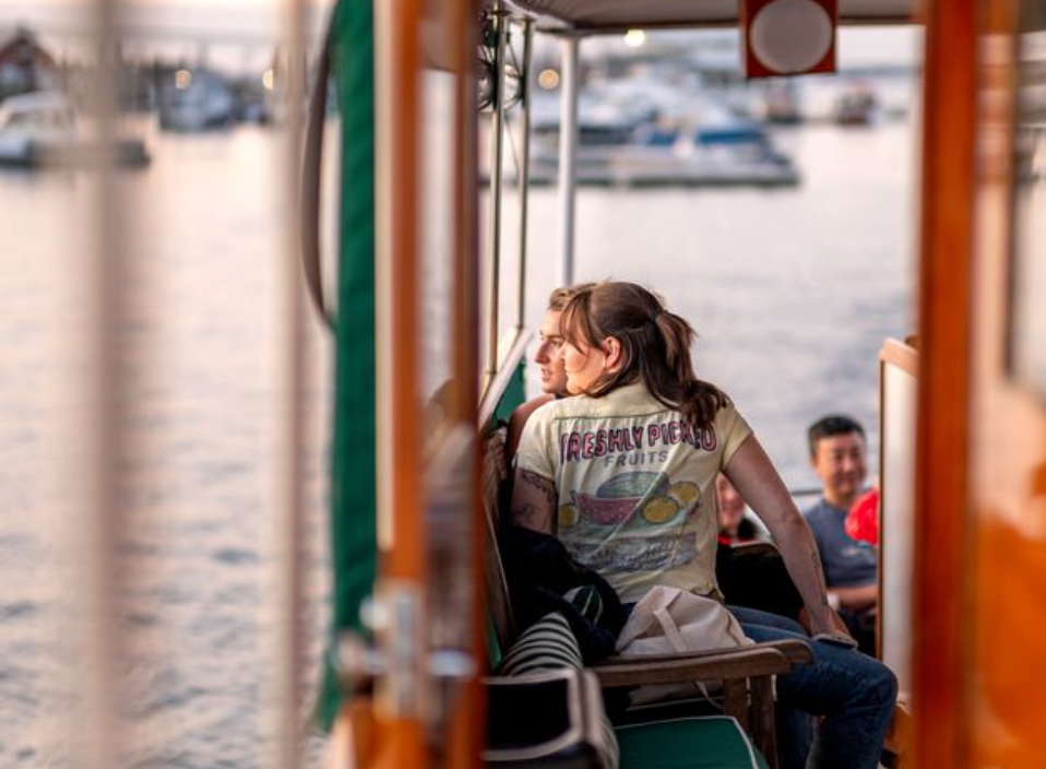 People sitting on a boat, looking out at the water and marina.