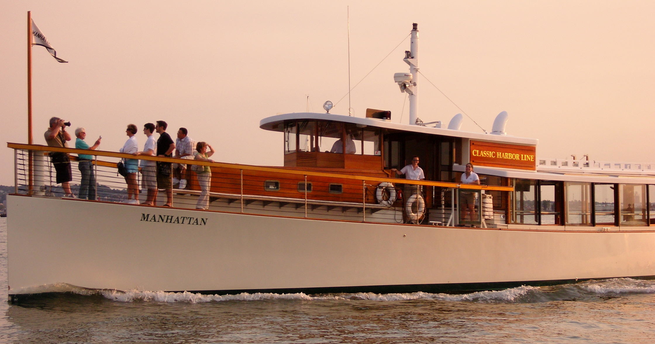 Group of people on a vintage-style boat cruising on calm water.