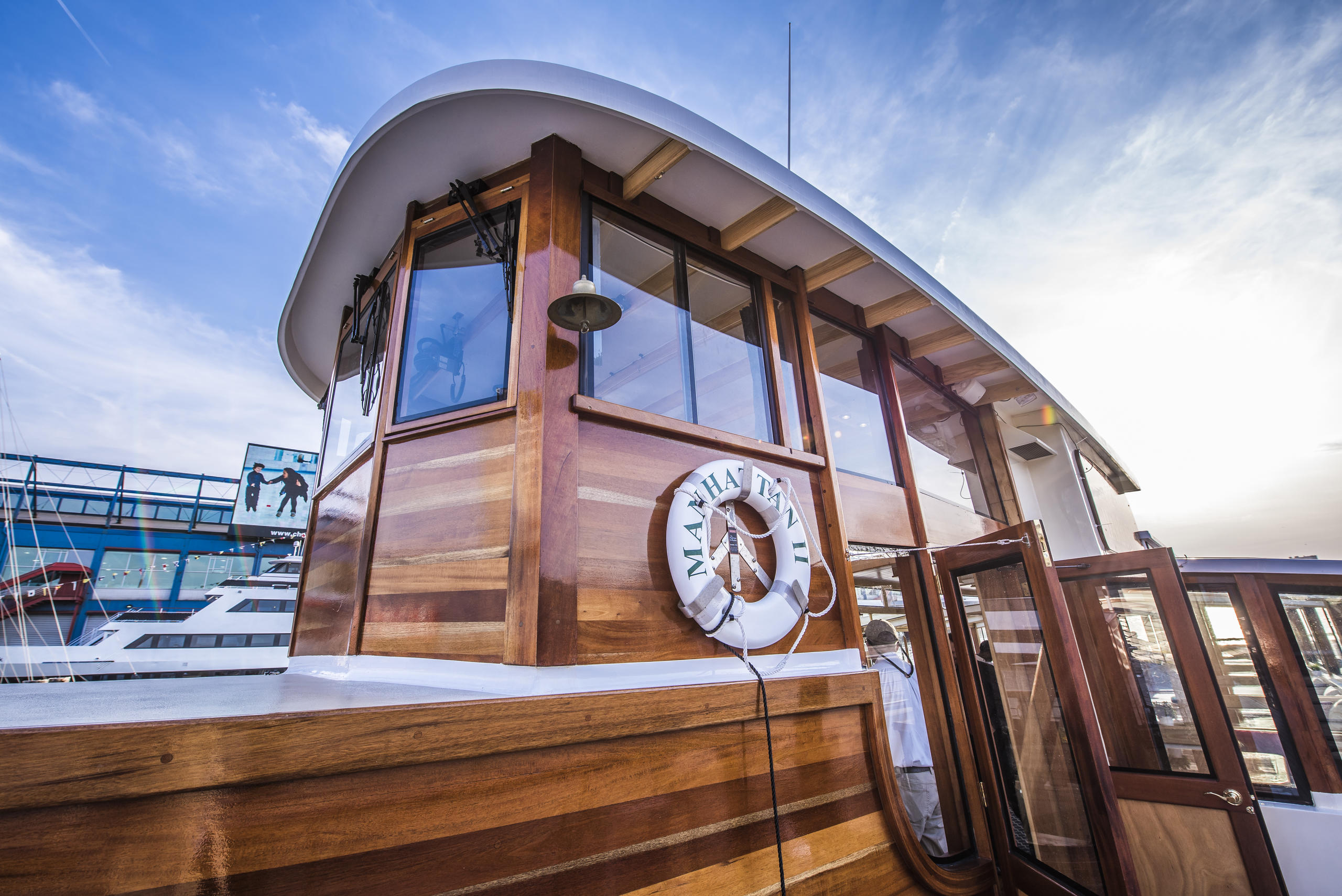 Wooden boat cabin with large windows and white lifebuoy on deck.