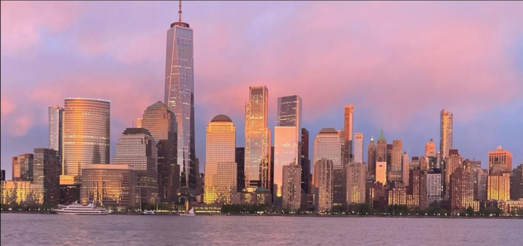 City skyline with tall buildings at sunset, pink clouds in the sky.