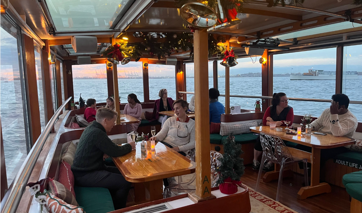 People dining on a boat with ocean view and festive decorations.