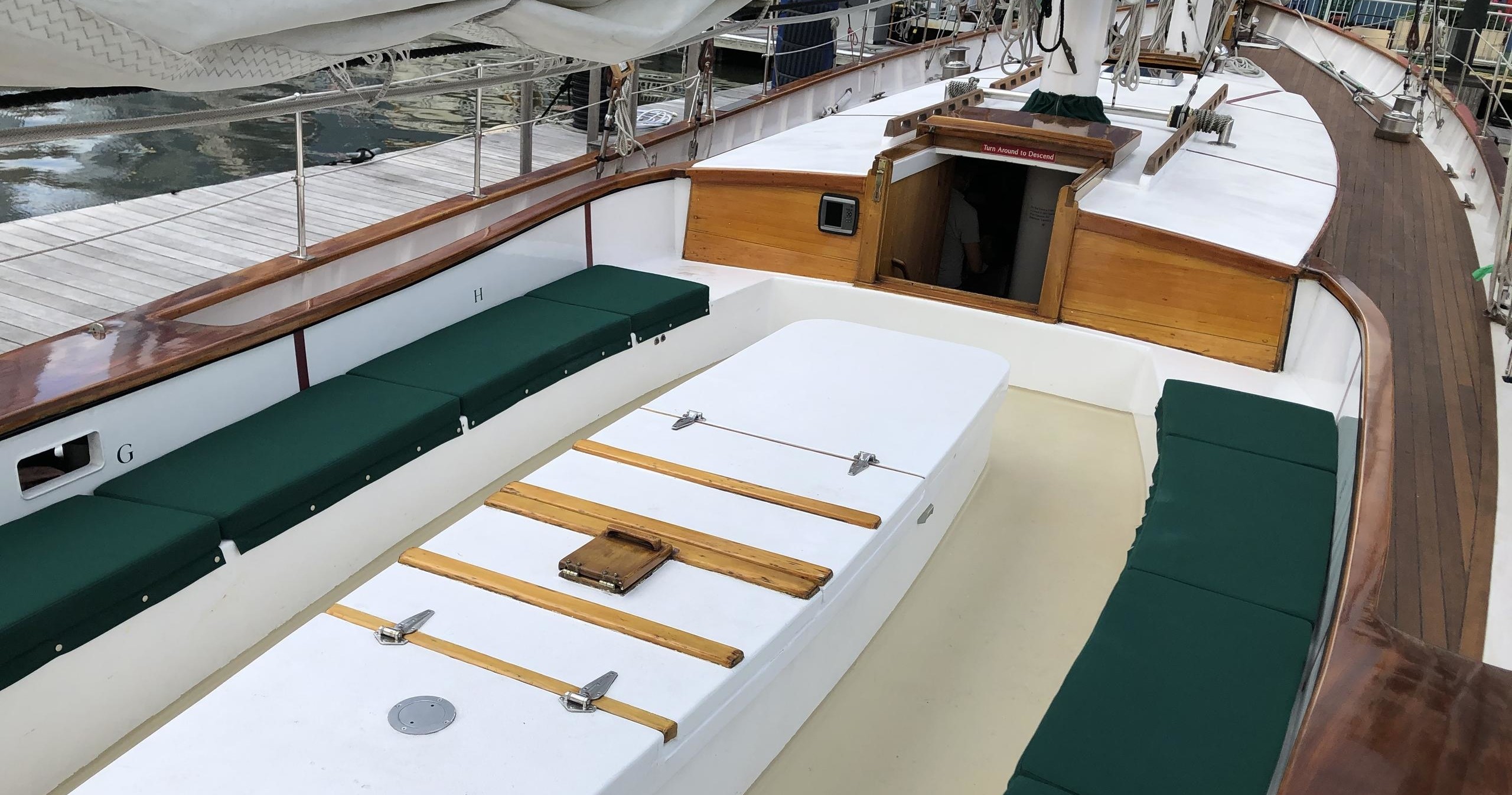 Boat deck with wooden benches and a central white hatch.