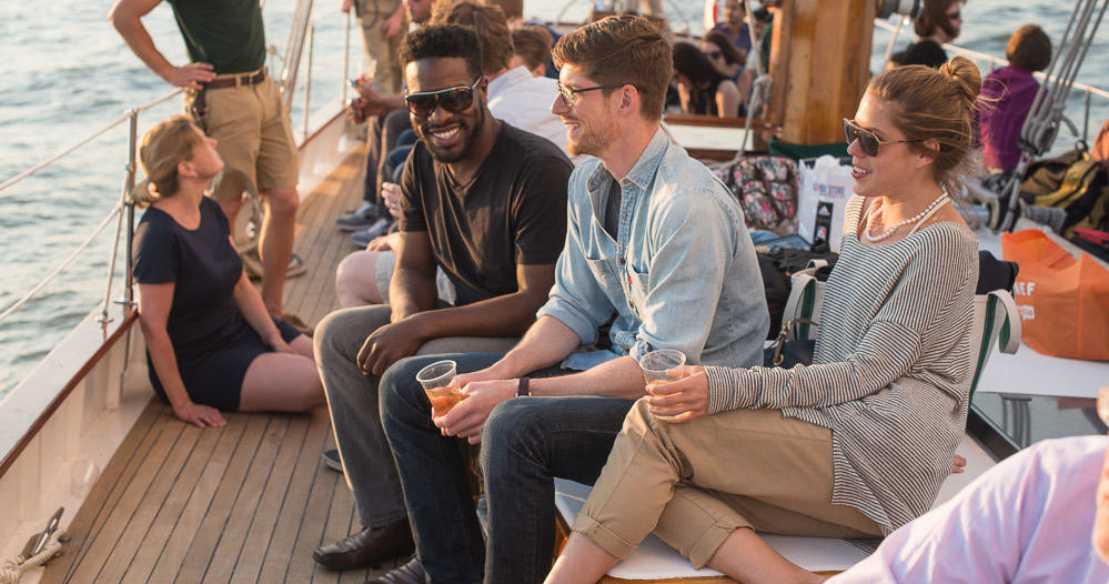 Group of people socializing on a boat deck with drinks.