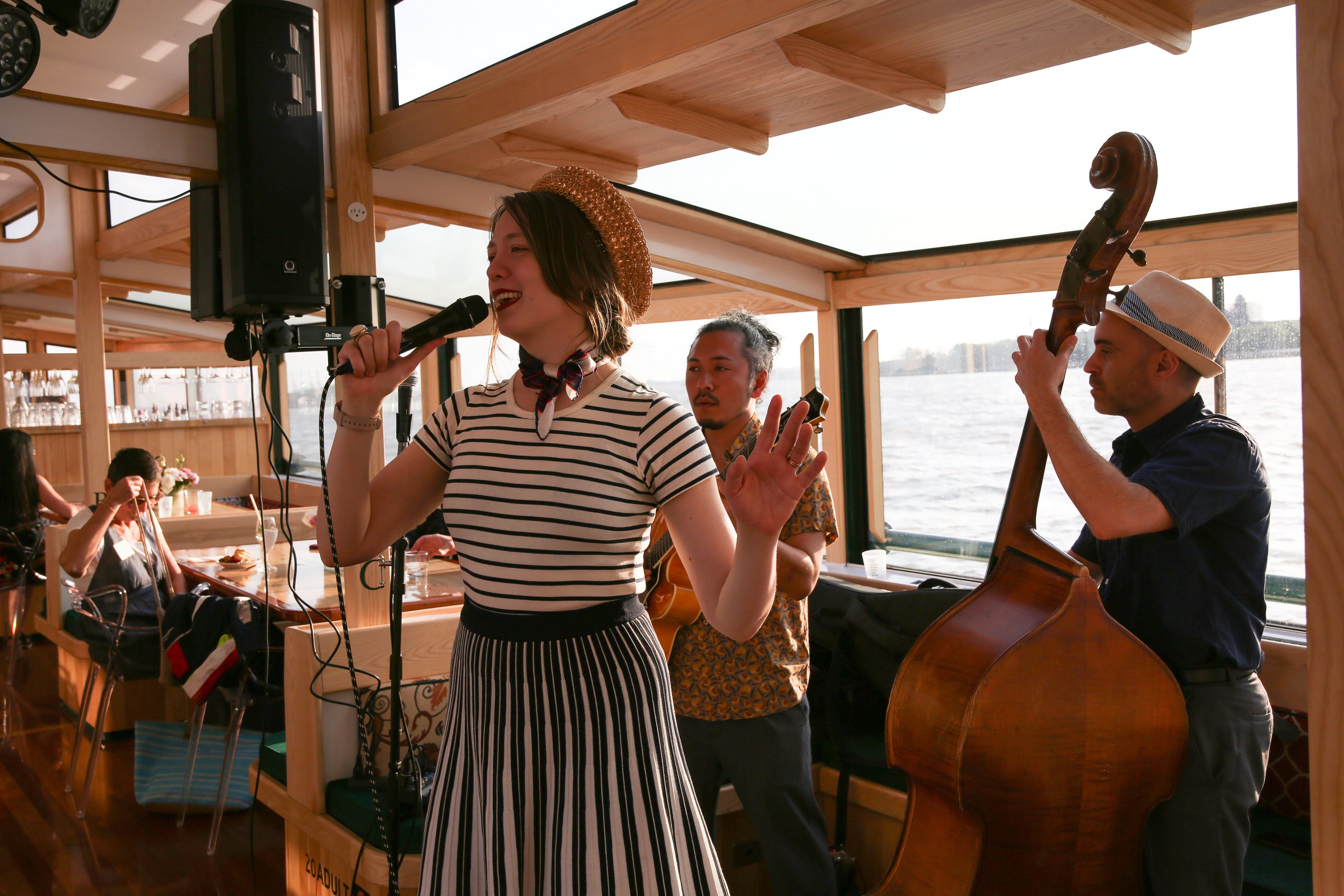 Woman sings with musicians on a boat.