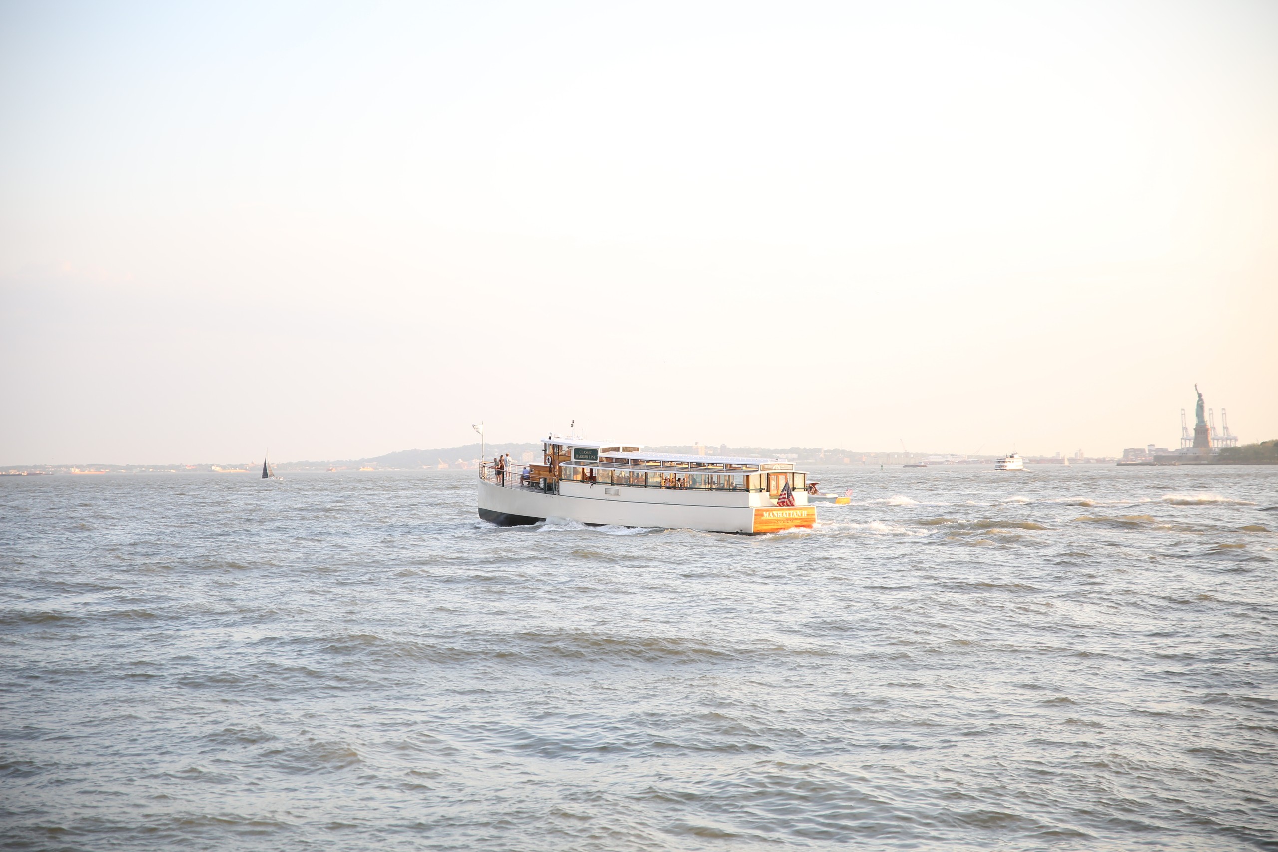 A ferry boat travels on a calm body of water under a clear sky.