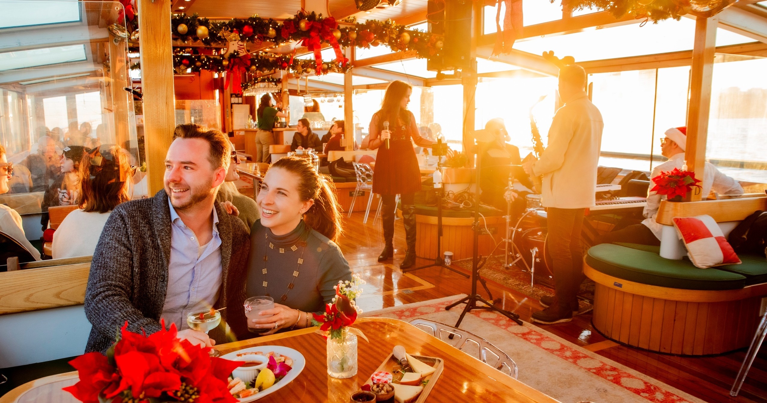 Couple smiling at a festive gathering onboard a boat at sunset.