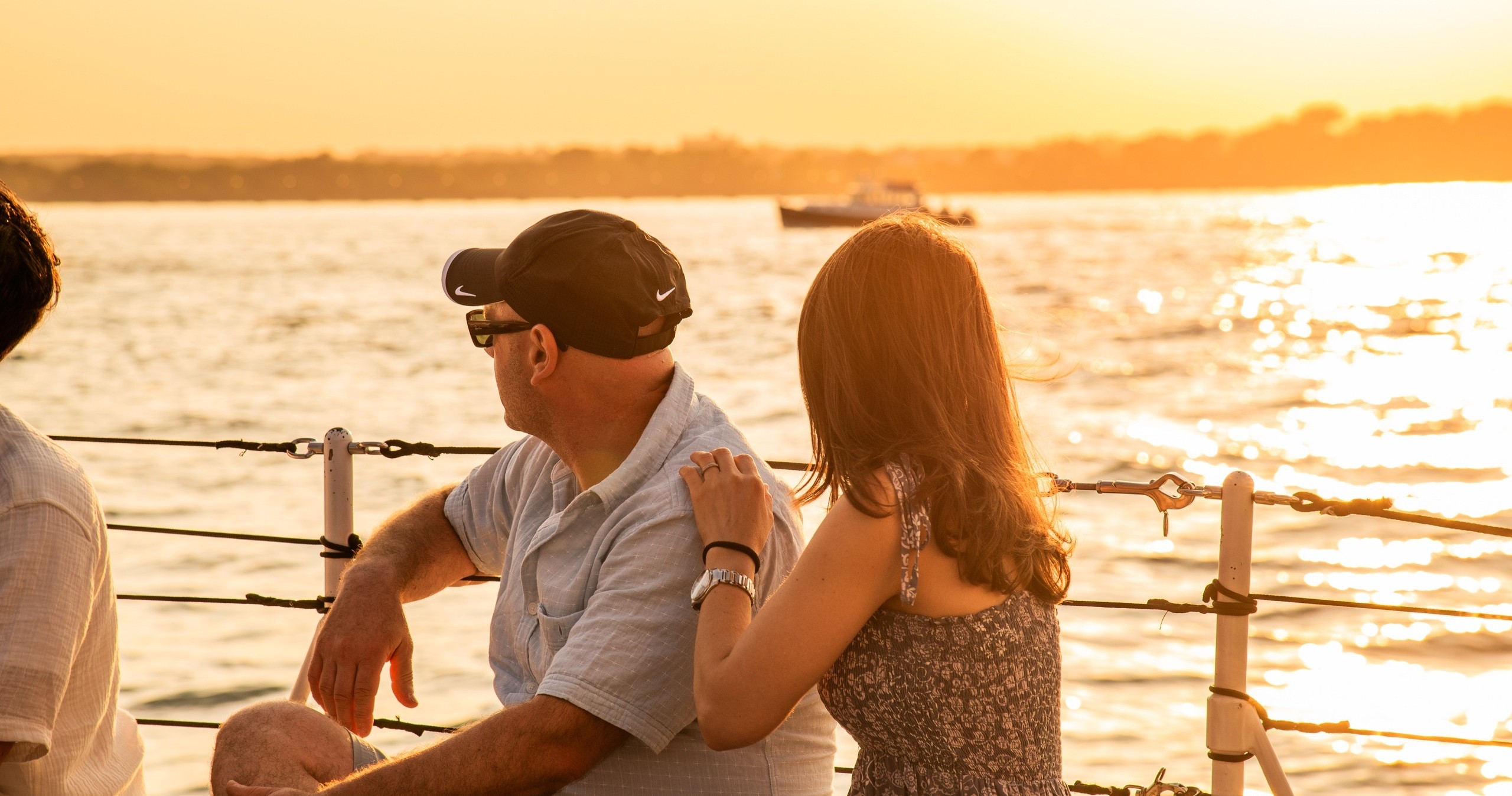 People on a boat watching sunset over calm water.