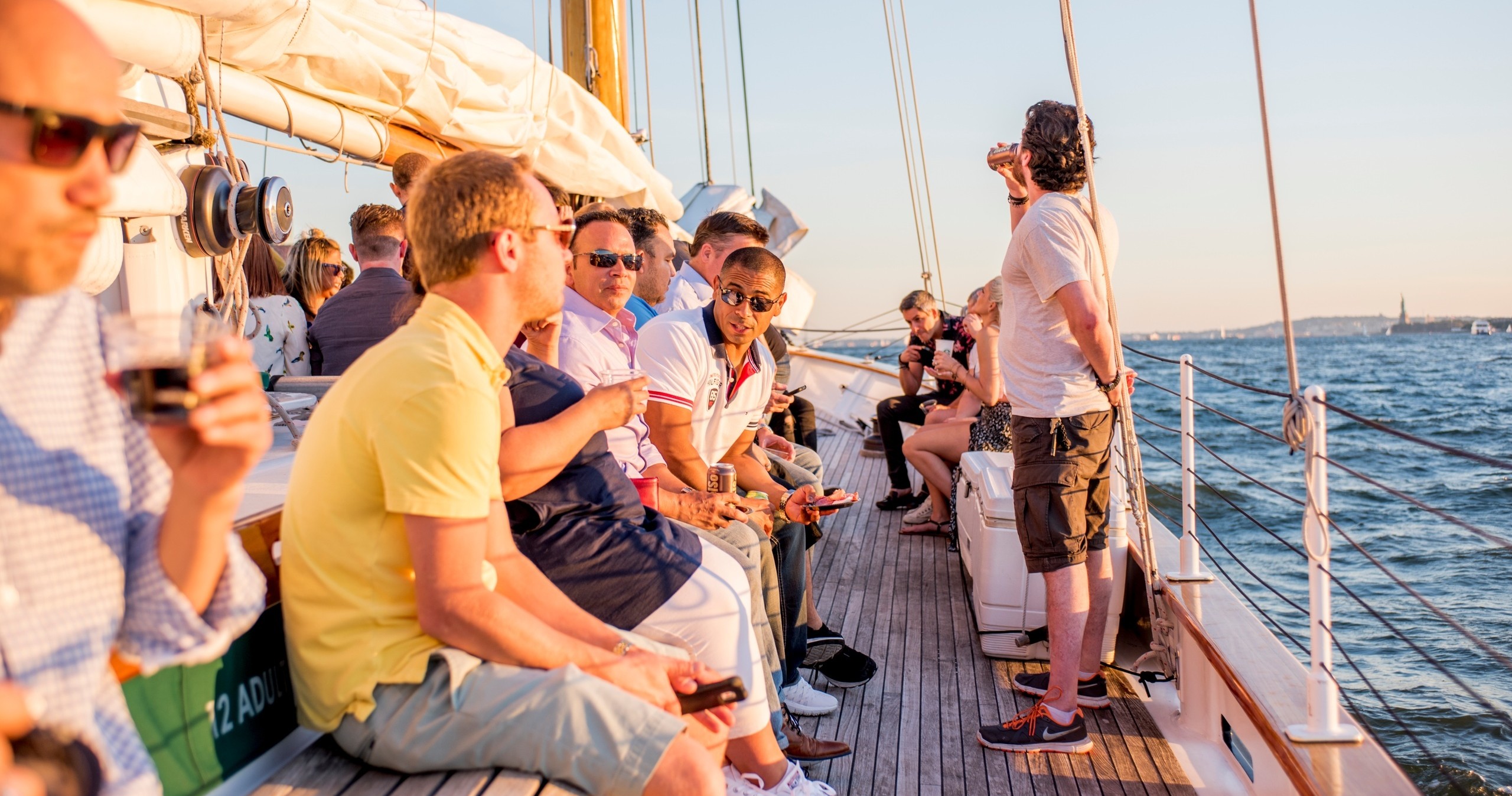 People socializing on a sailboat at sunset on the ocean.