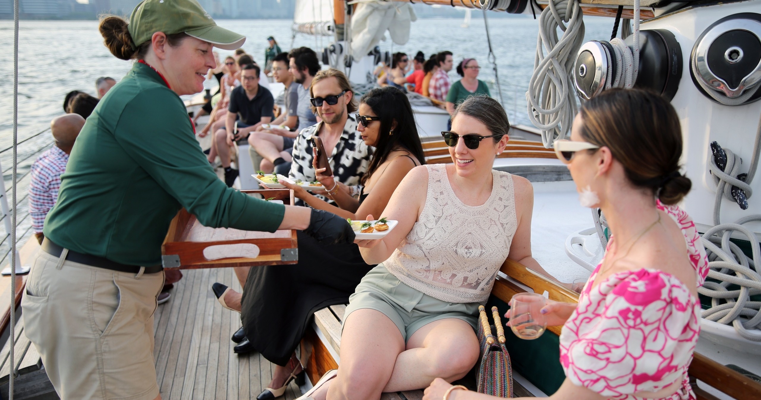 People on a boat enjoying food served by a staff member.