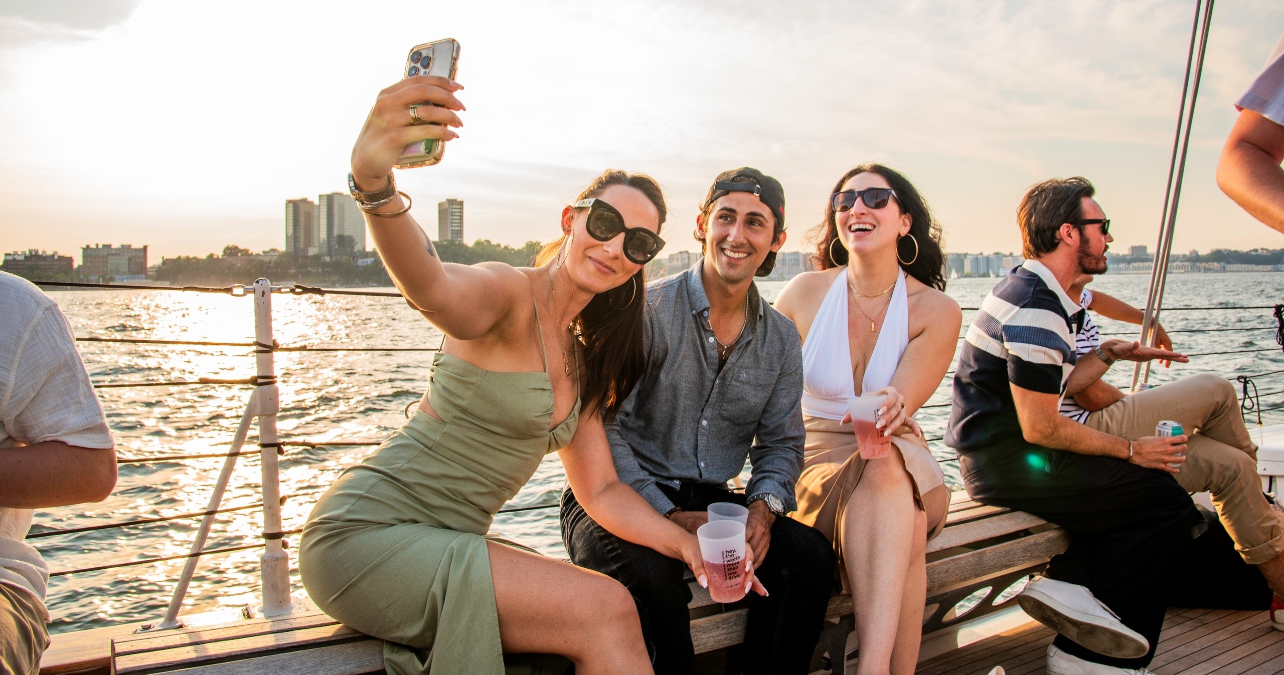 Group taking a selfie on a boat at sunset.