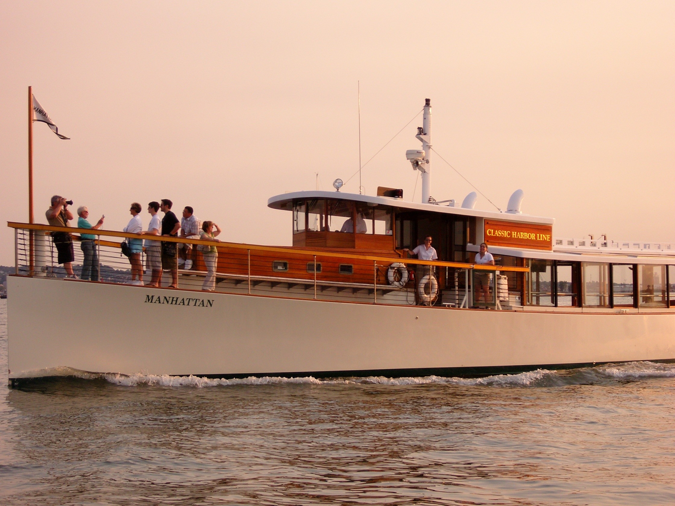 A group of people on a white yacht named Manhattan on the water.