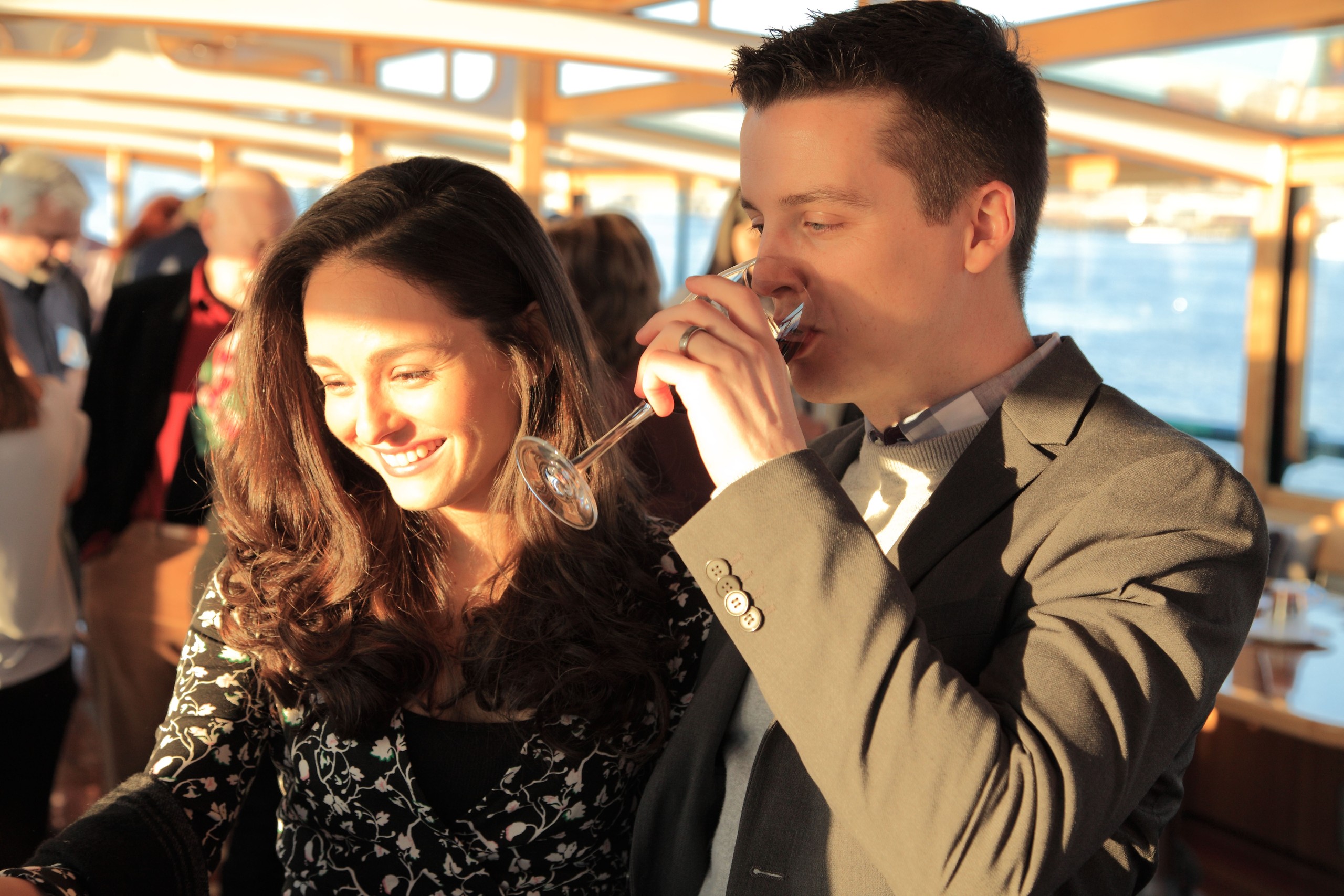 A couple enjoying drinks at an event, smiling in warm lighting.