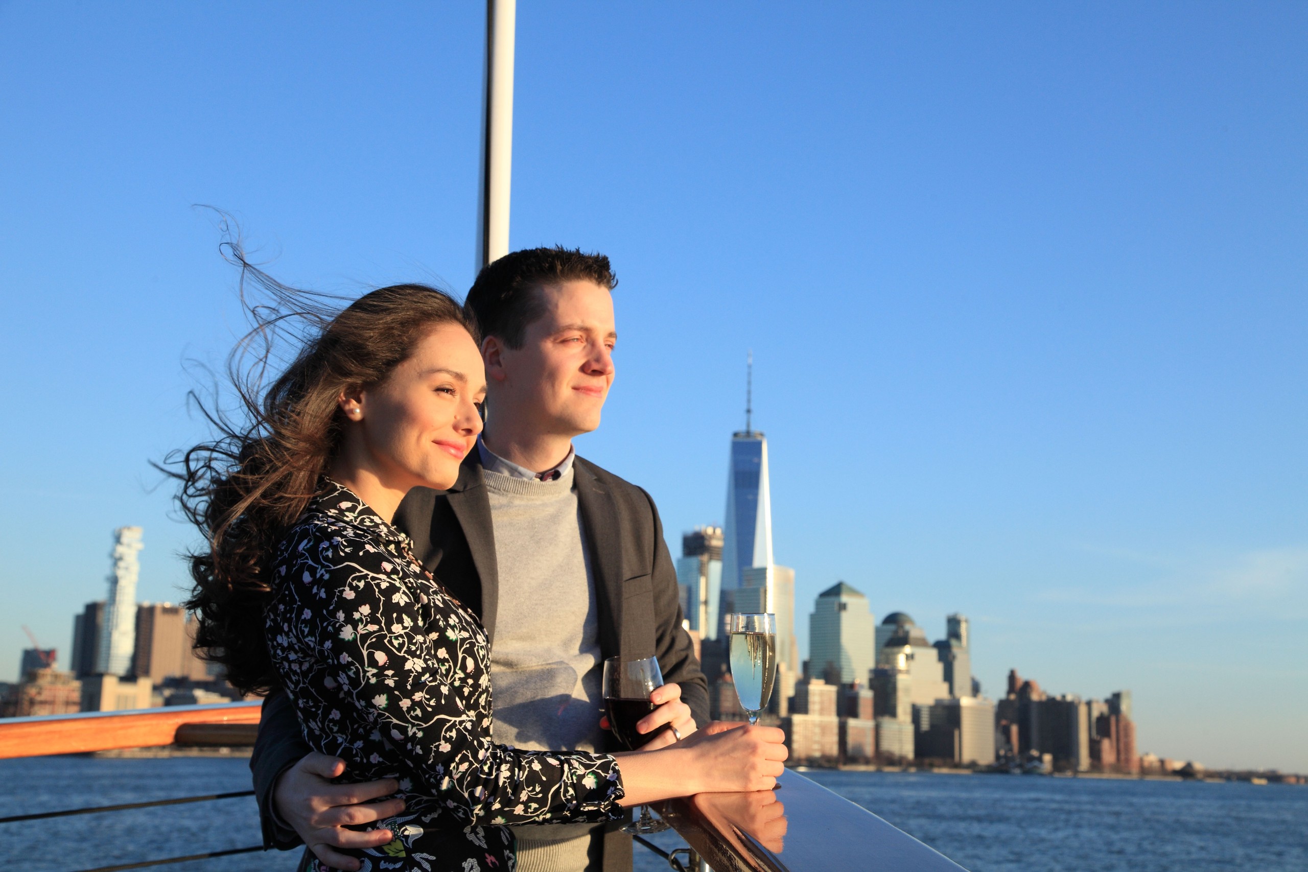 Couple on boat enjoying city skyline view with wine glasses.