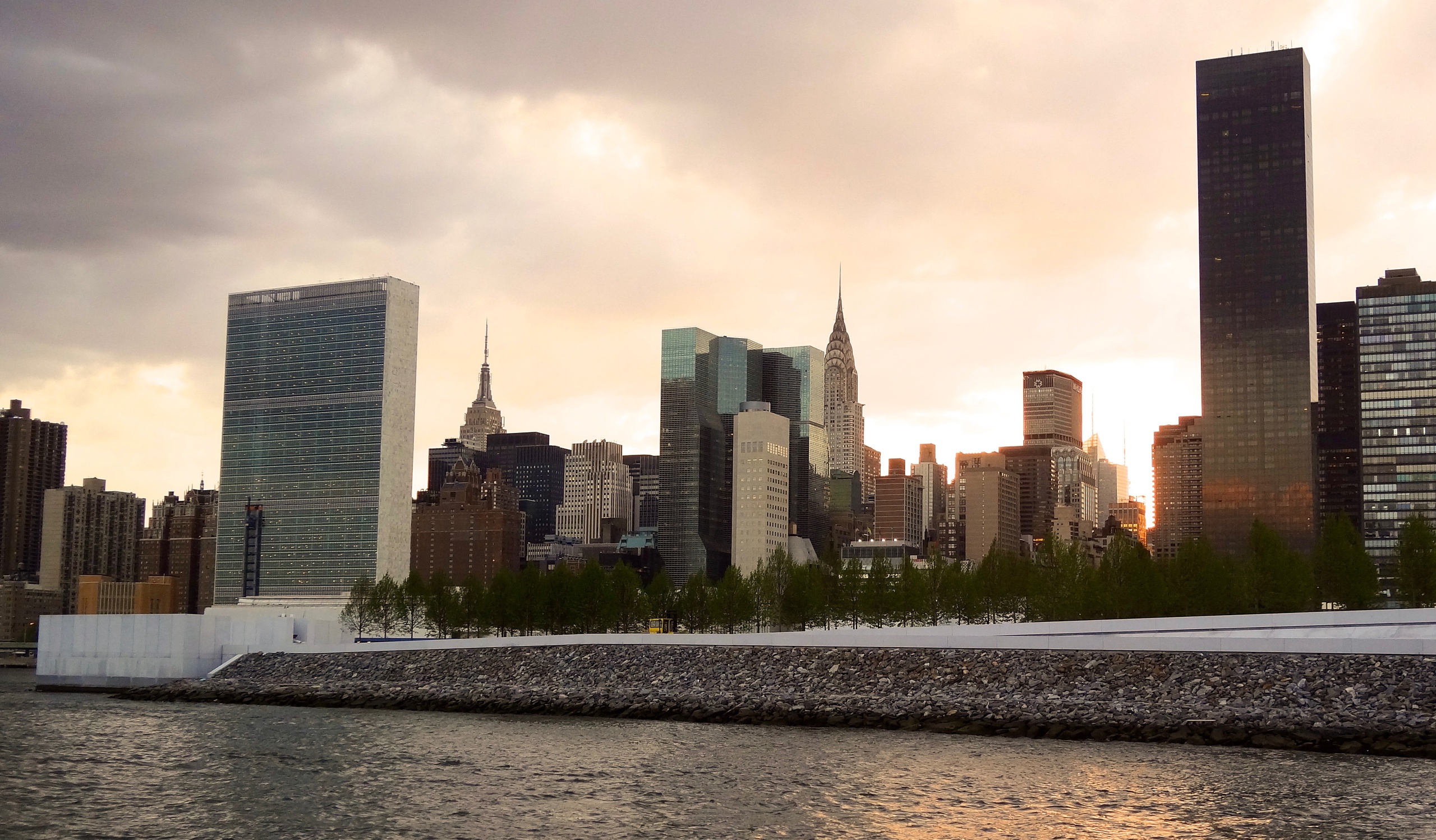 New York City skyline at sunset with water in foreground.