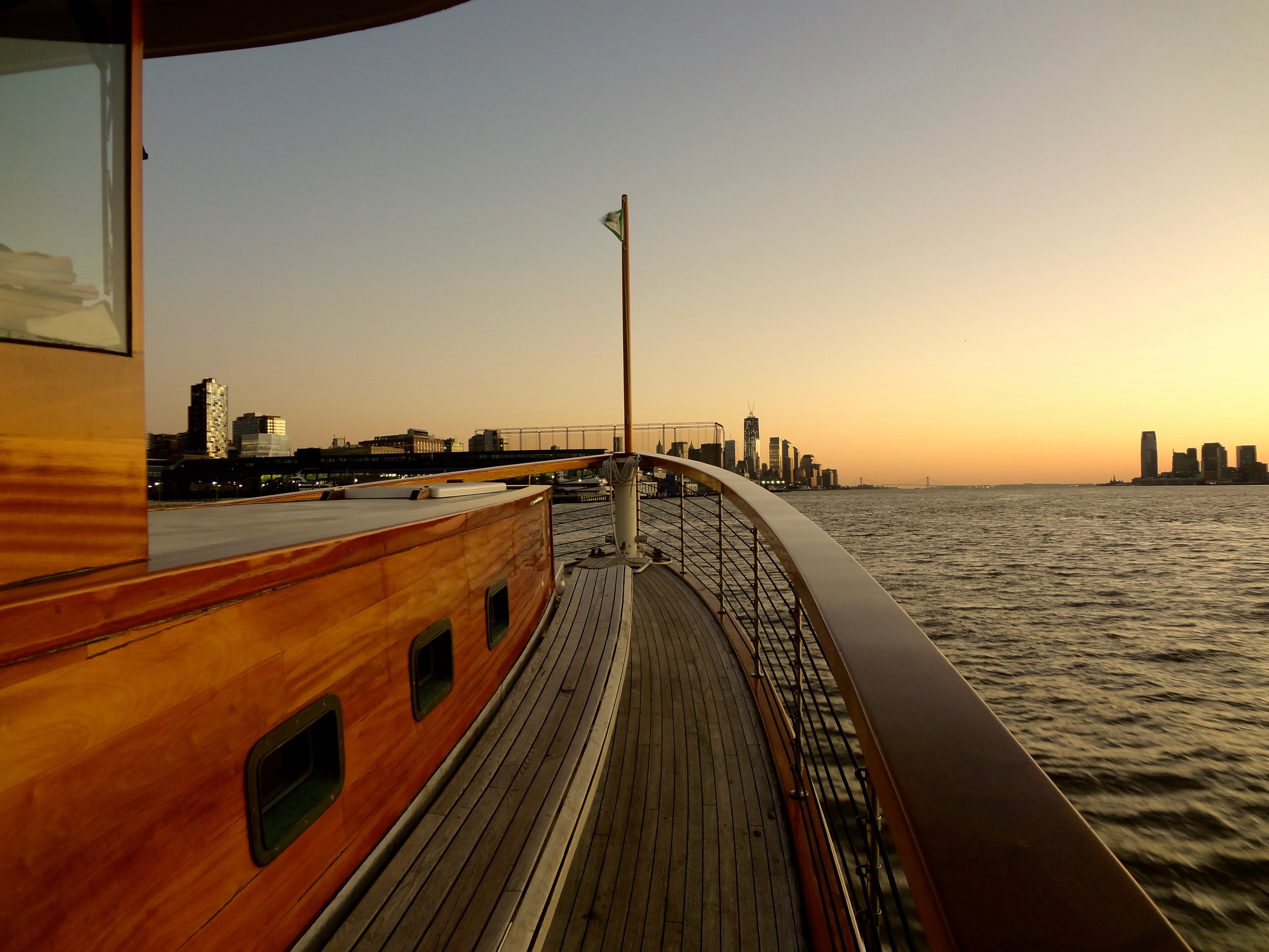 Boat deck at sunset with city skyline in the background.